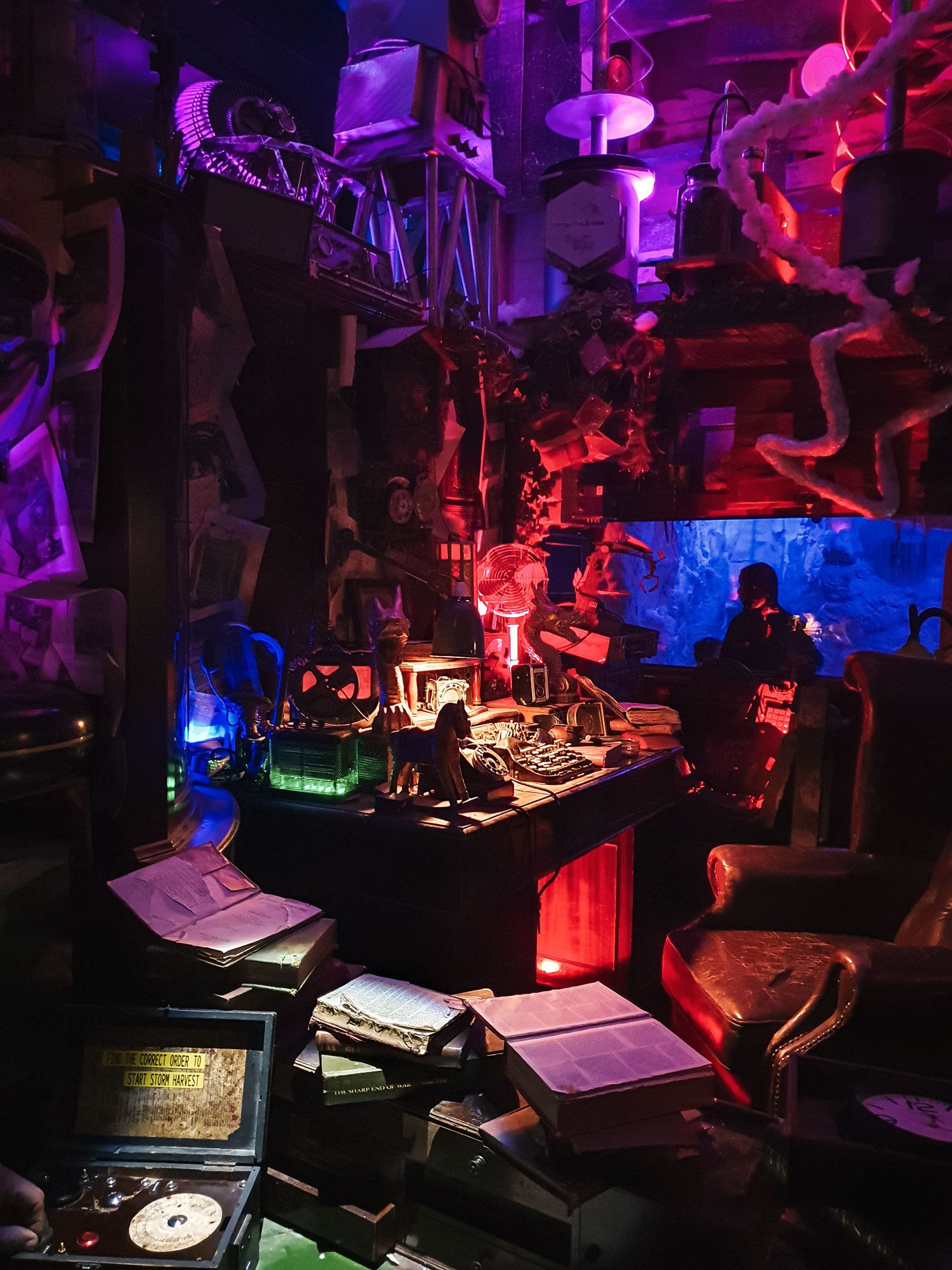 Musicians perform in a dark venue illuminated by vibrant purple and red stage lighting creating a moody atmosphere.