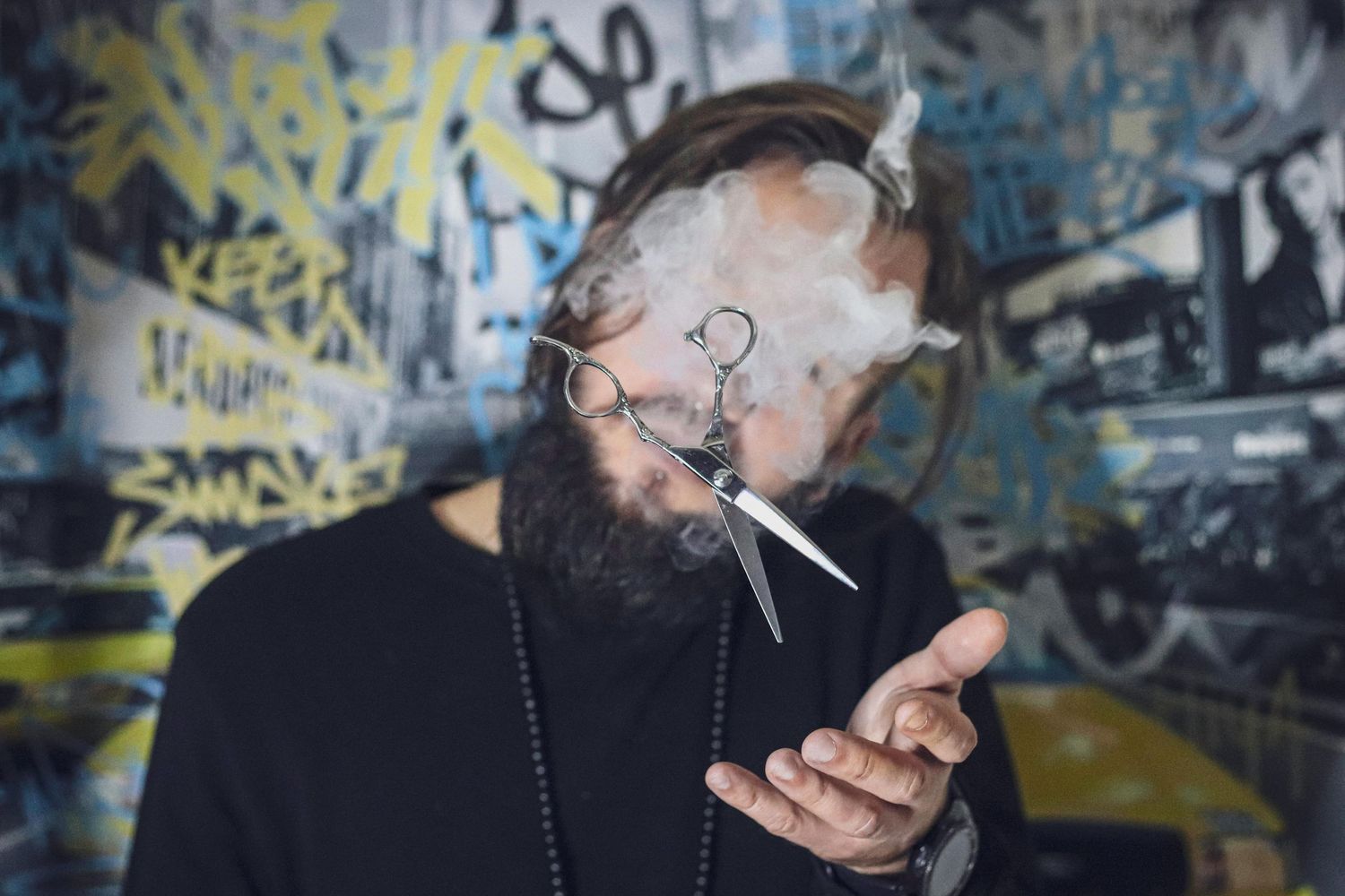 Person smoking while sitting against graffiti covered wall with colorful street art and urban textures in background.