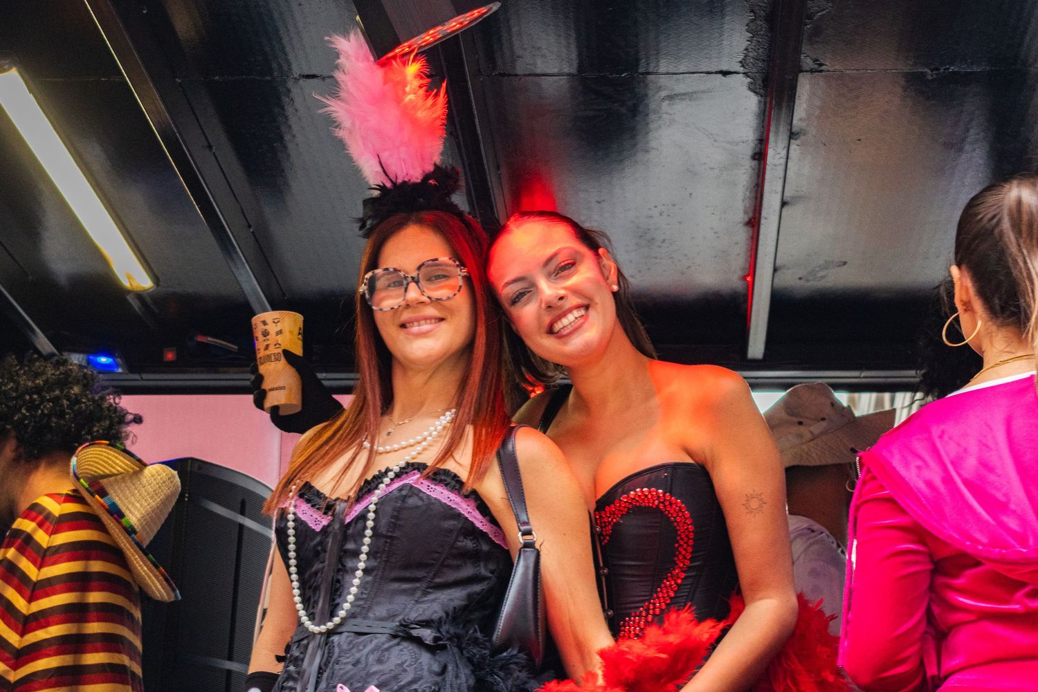 A group of people enjoying a festive party with pink and red lighting at a nighttime event.