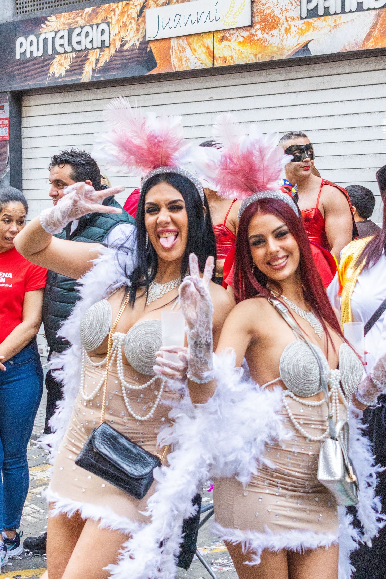 A group of women celebrate in white feather boas and beige outfits at what appears to be a bachelorette party.