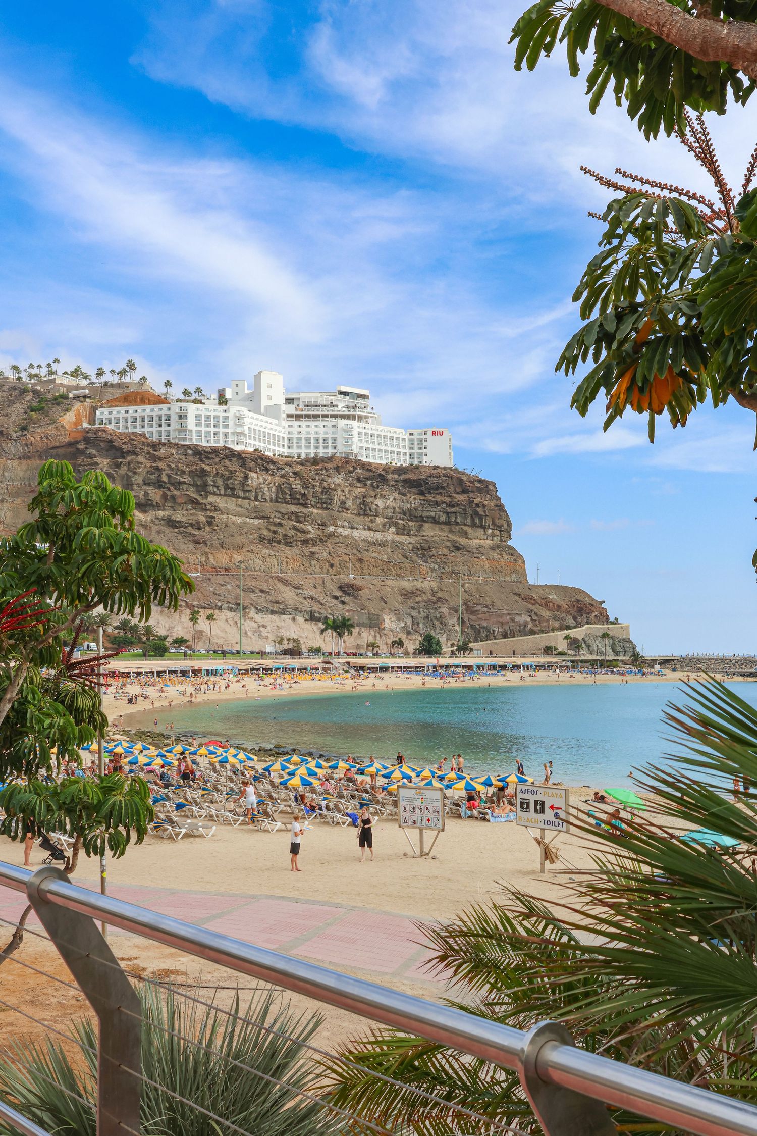 Beach resort built on rocky cliffs overlooking turquoise waters at Playa de Amadores in Gran Canaria, Spain.