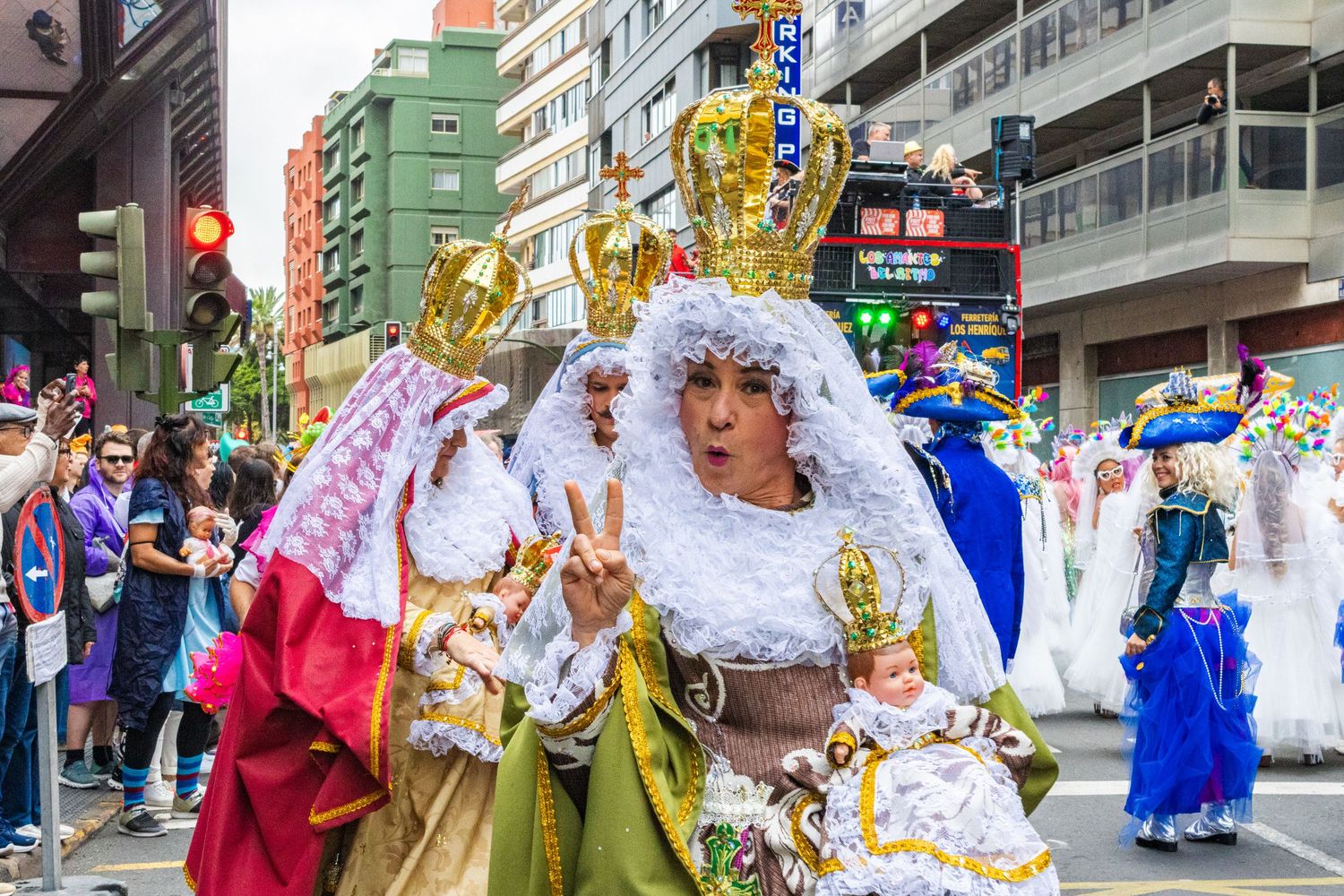 Traditional dancers in colorful costumes perform during a cultural festival parade in an urban street setting.