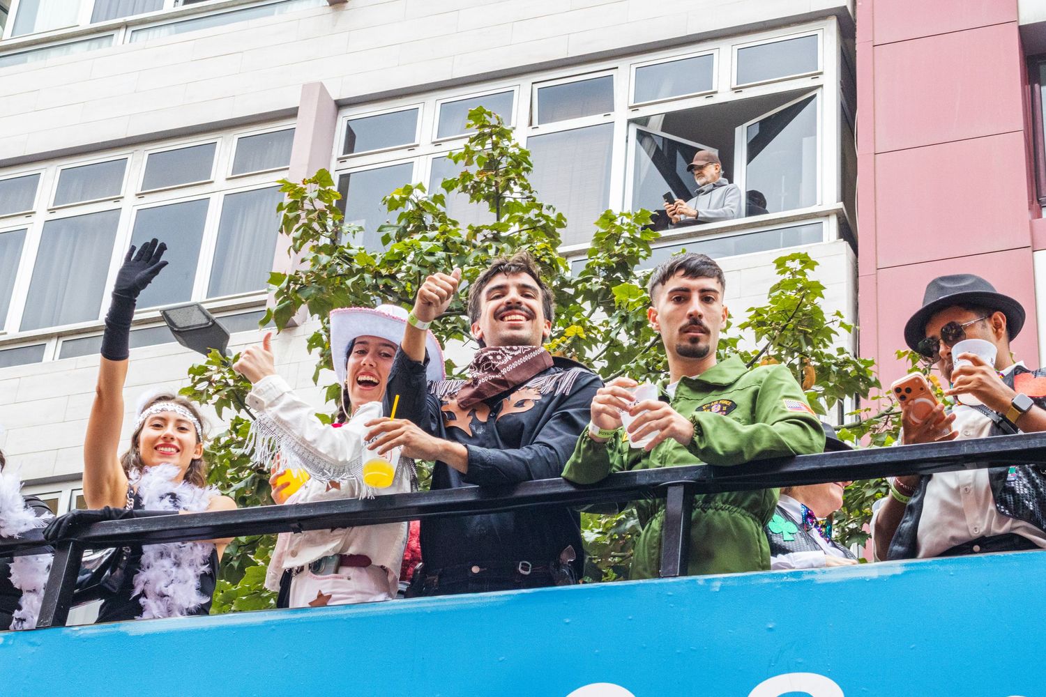Excited fans cheer and celebrate from a balcony overlooking a crowd during a sporting event.