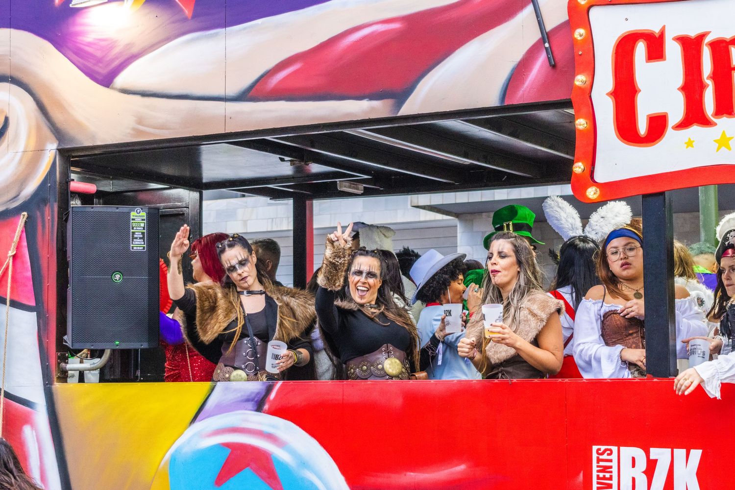 People celebrating on a decorated party float with red and blue designs during a summer festival.