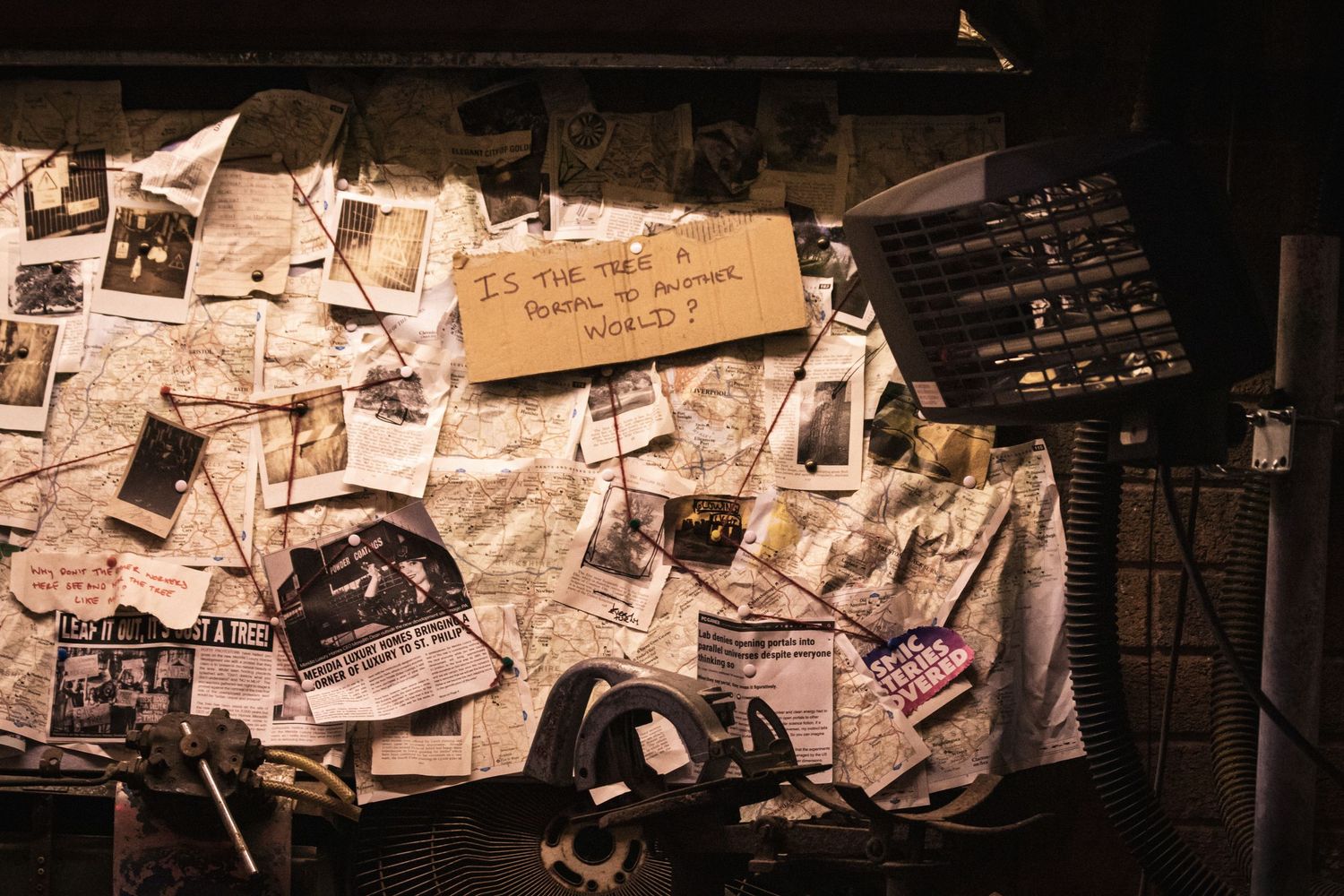 A dark hallway with walls covered in old photos, notes, and papers creating an eerie investigative atmosphere.