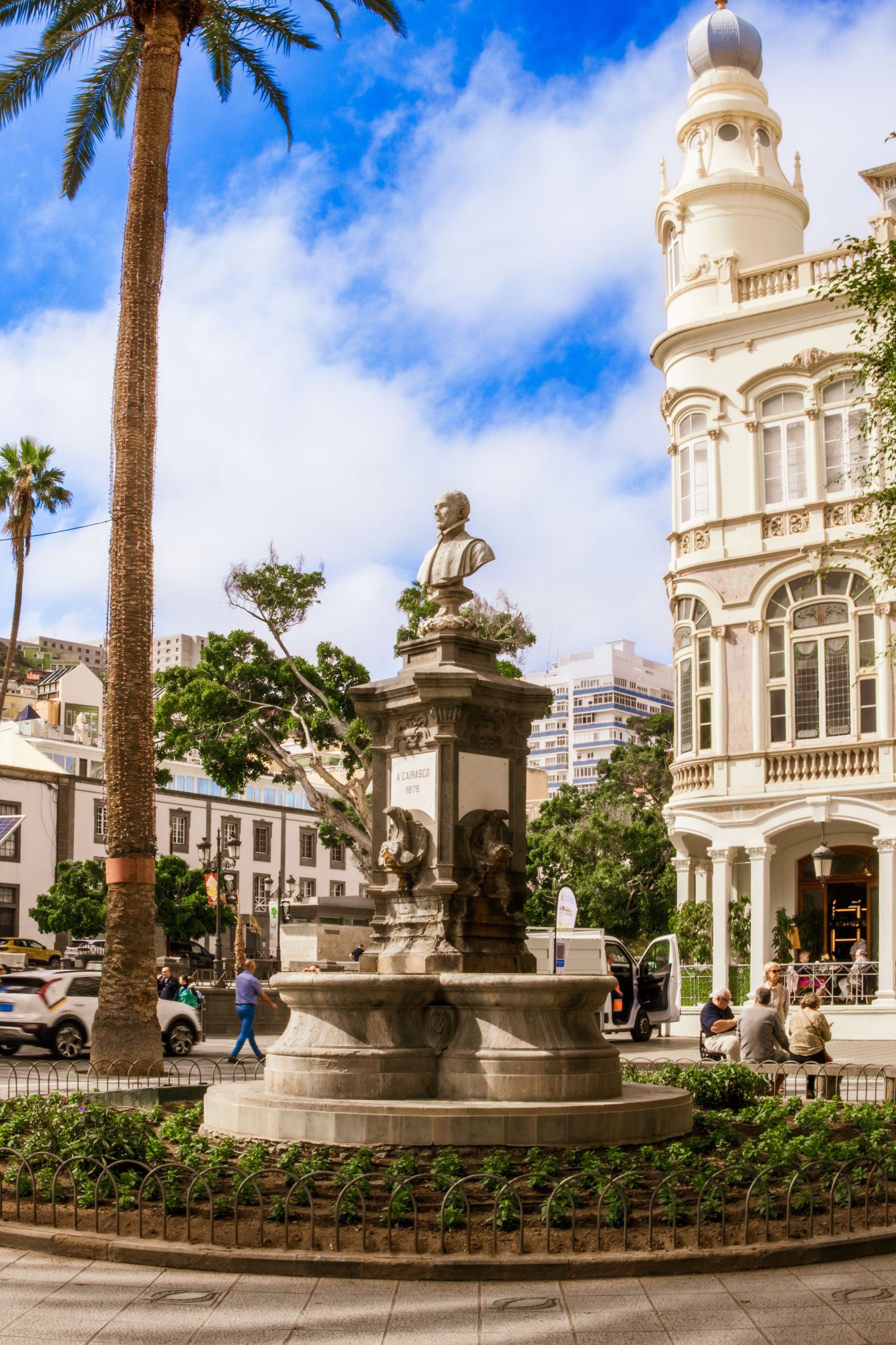 Historic white colonial building with palm trees and ornate architecture in tropical setting under bright blue sky.