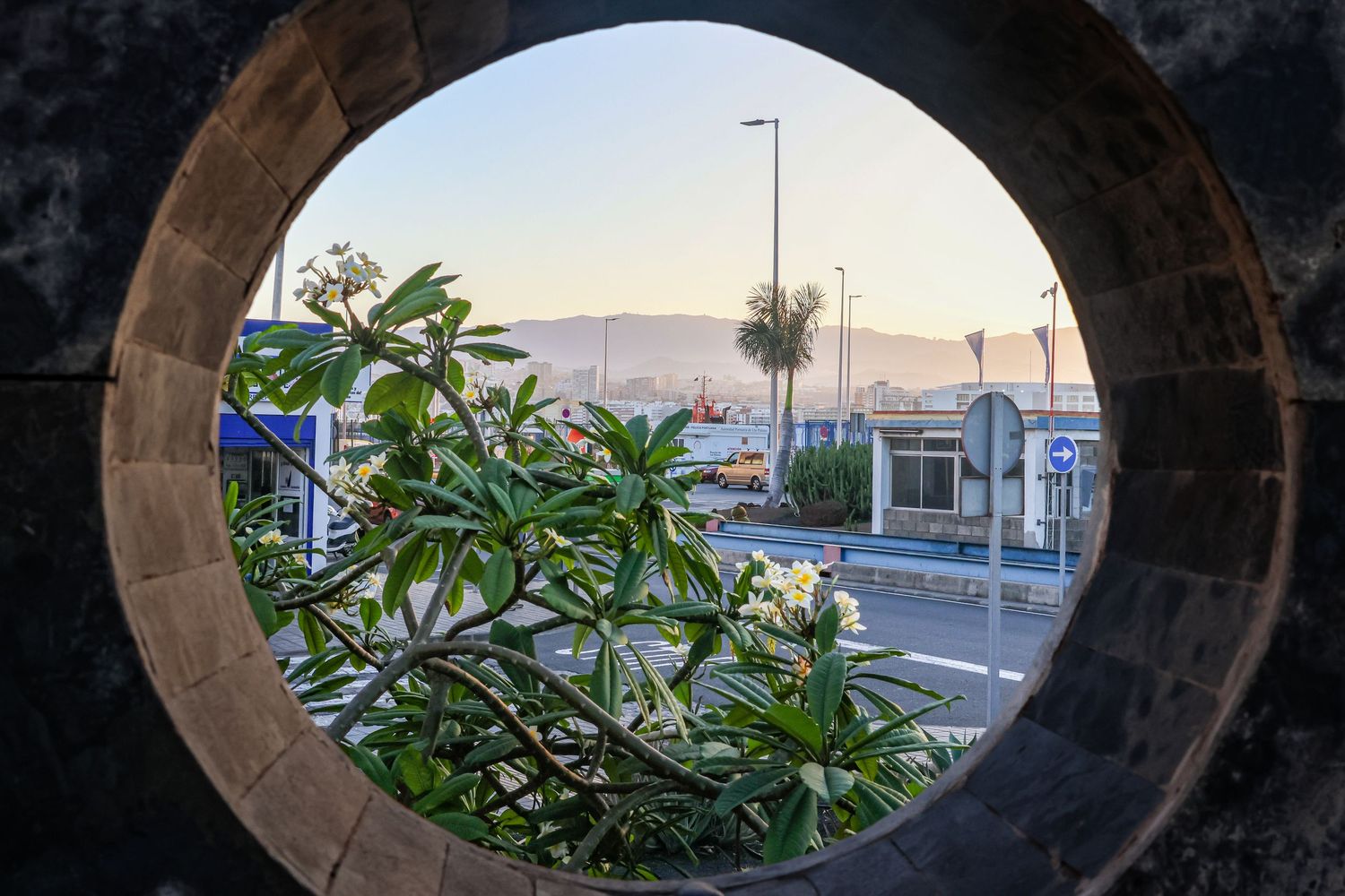Series of stone archways framing a harbor view at sunset.