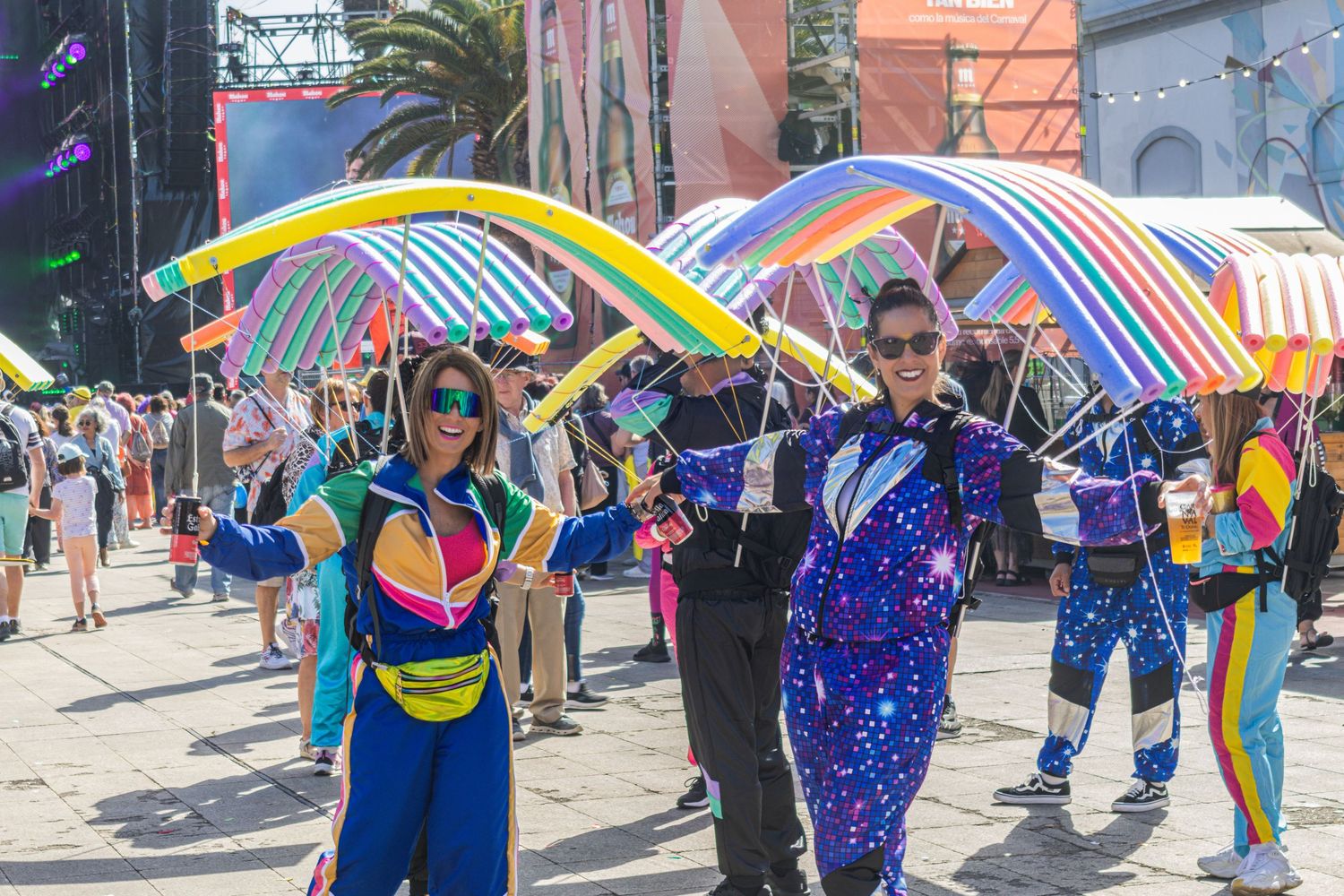 Colorful crowd of festival goers with umbrellas and parasols dancing at an outdoor summer celebration.