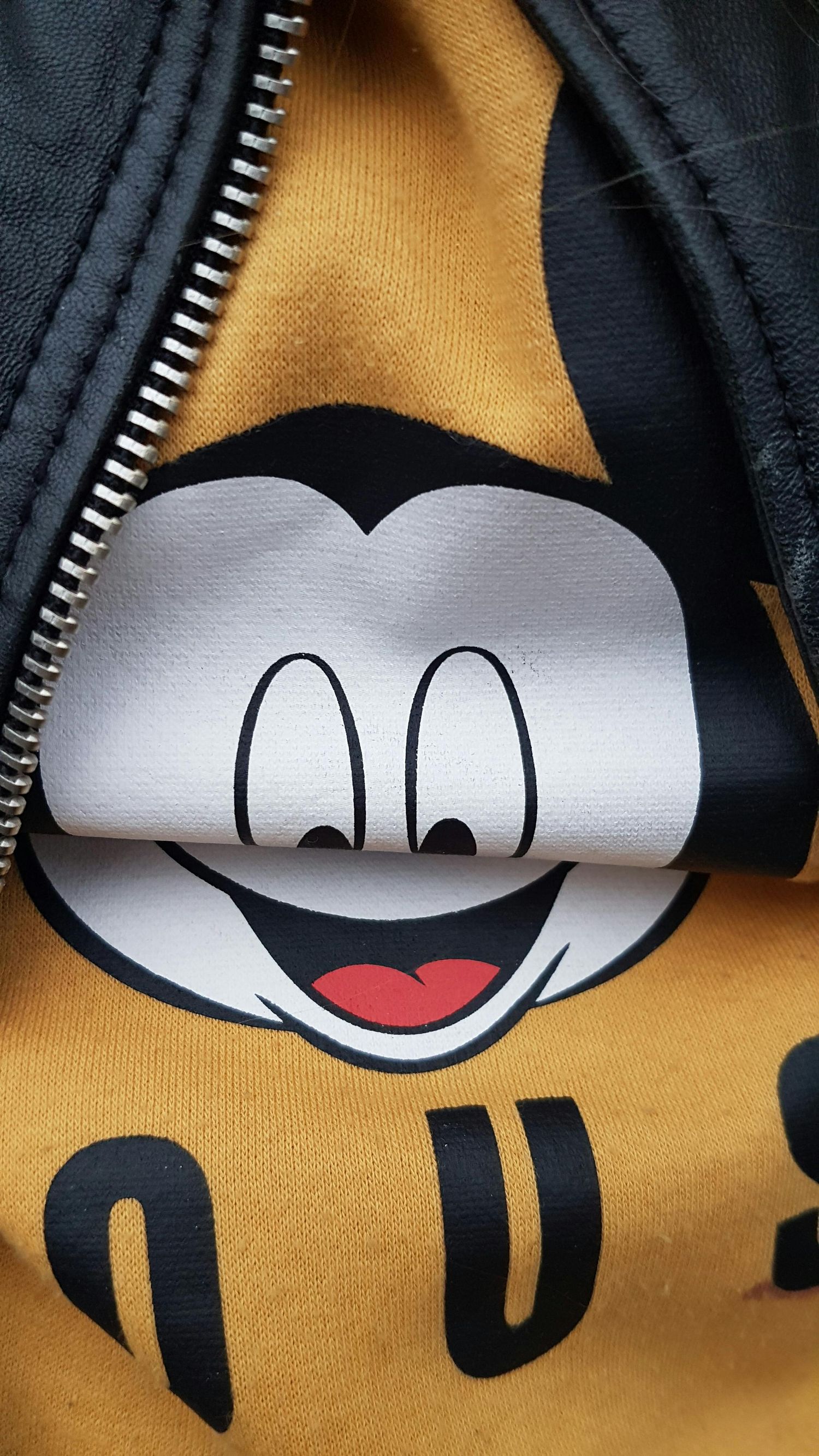 Close-up sequence showing a zipper opening to reveal Mickey Mouse's iconic face design on yellow fabric.