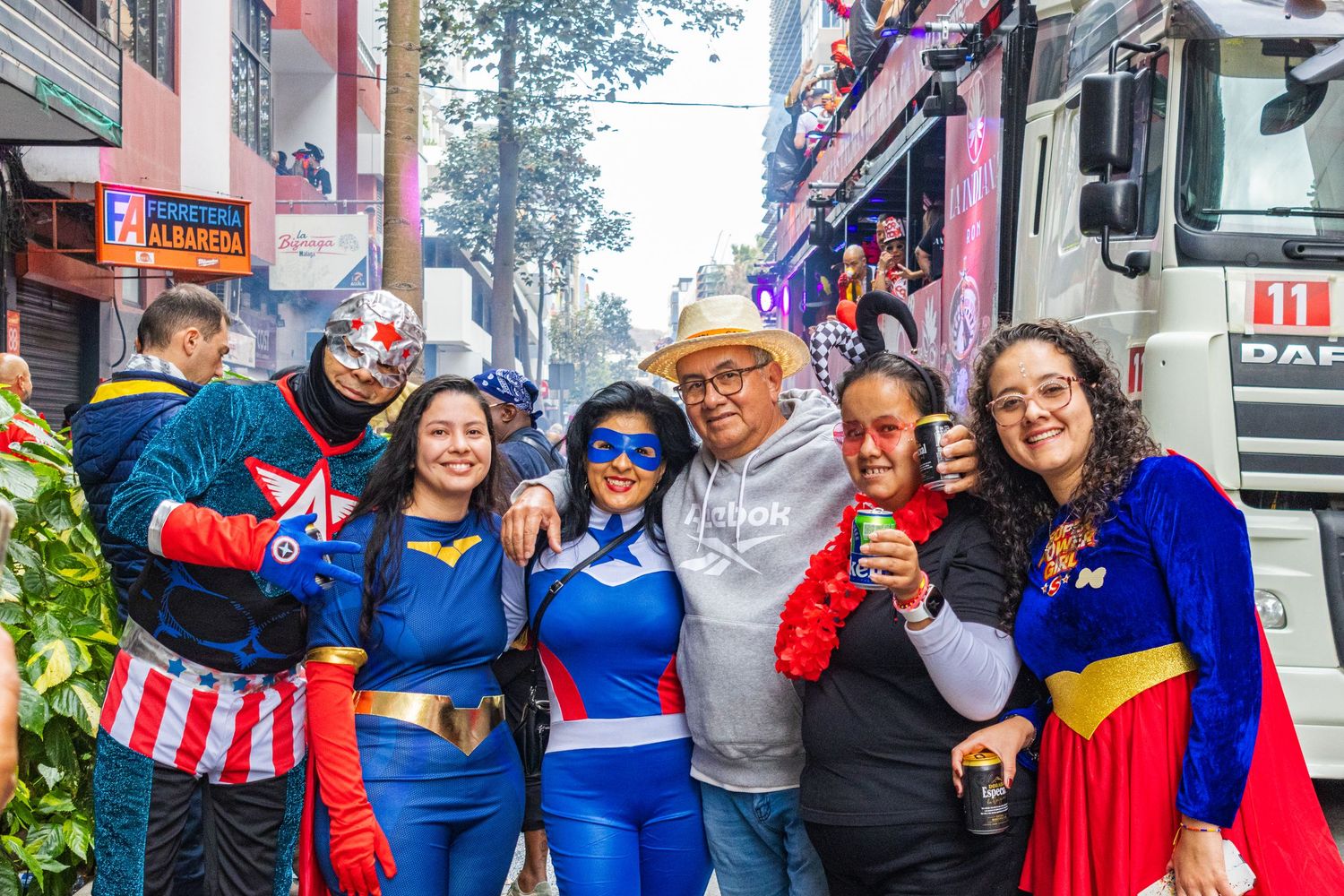 A group wearing colorful superhero costumes poses together at a street event.