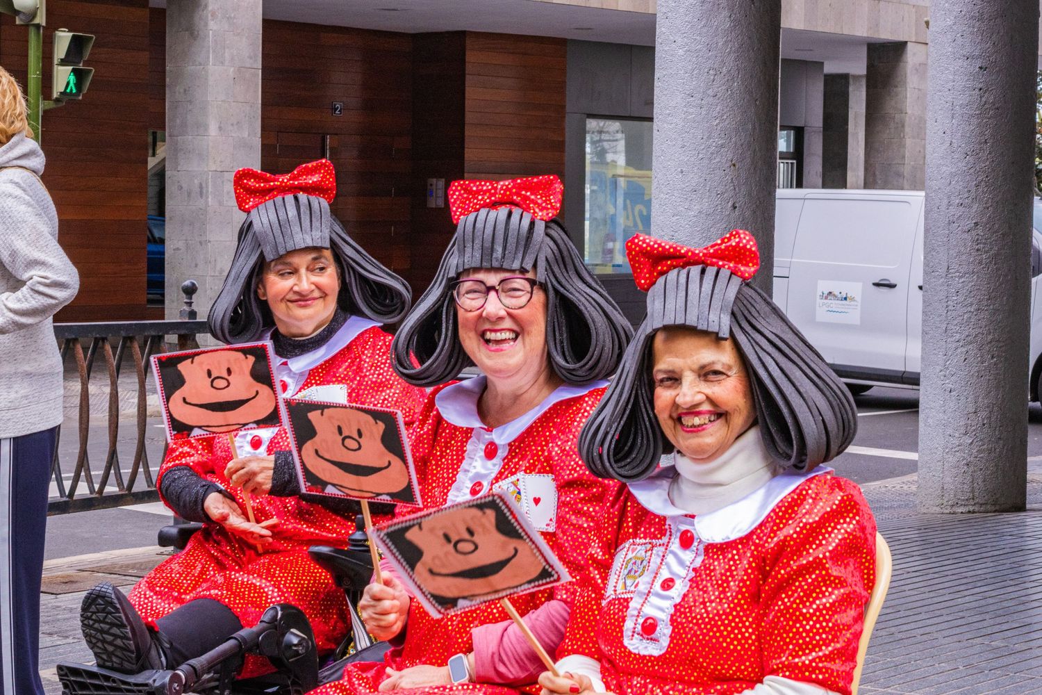 A group wearing matching red holiday sweaters and knit hats pose together at an indoor gathering.