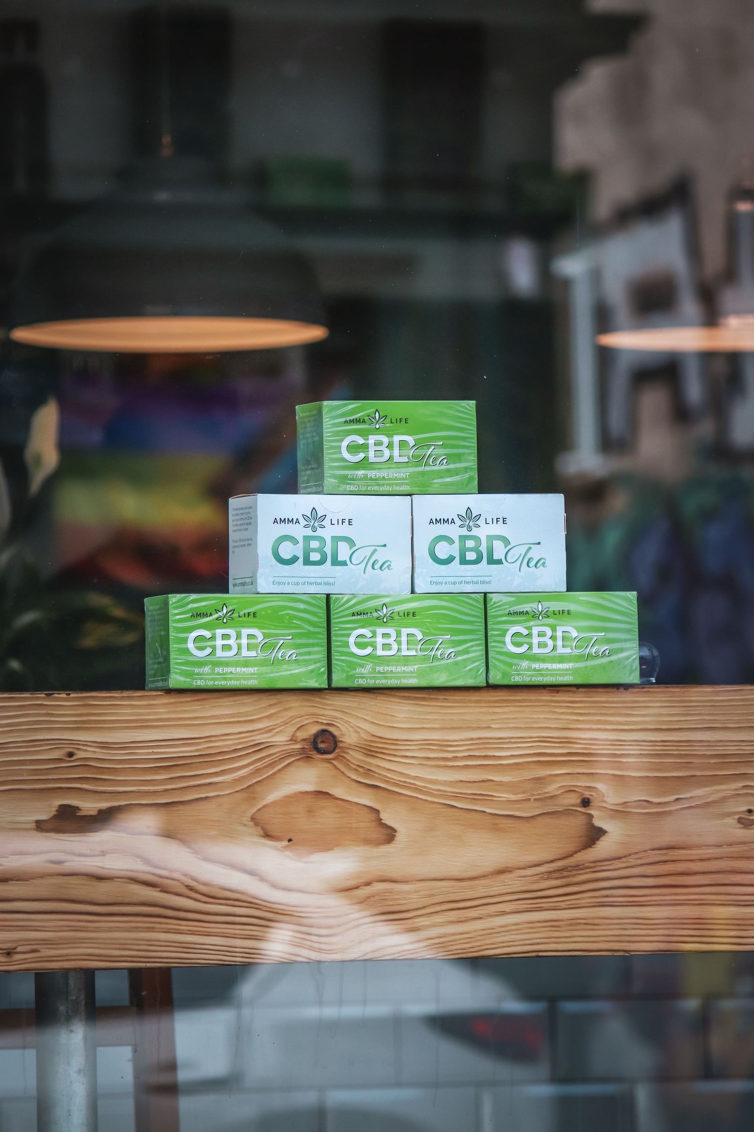 Green CBD product boxes displayed on rustic wooden shelf in retail store window.