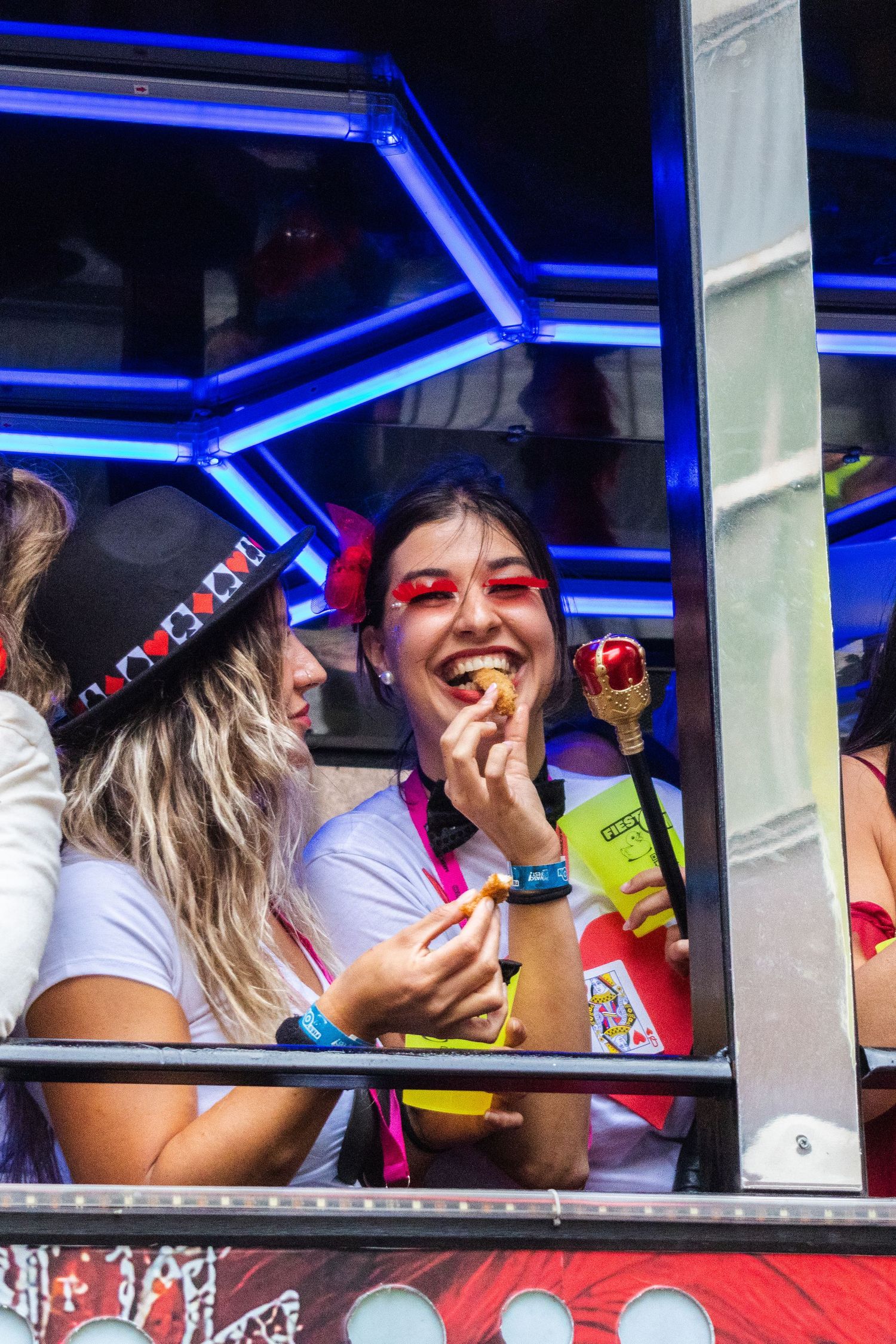 Passengers smile and laugh while riding in a party bus with bright blue LED lighting and neon decorations.