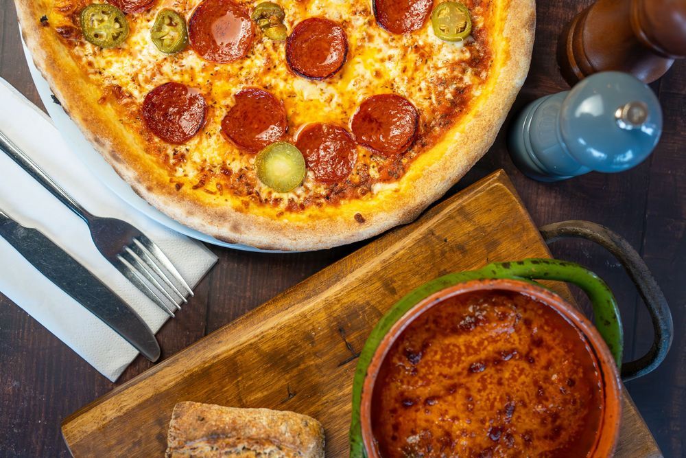 Delicious pepperoni pizza with melted cheese and olives served on a rustic wooden cutting board.