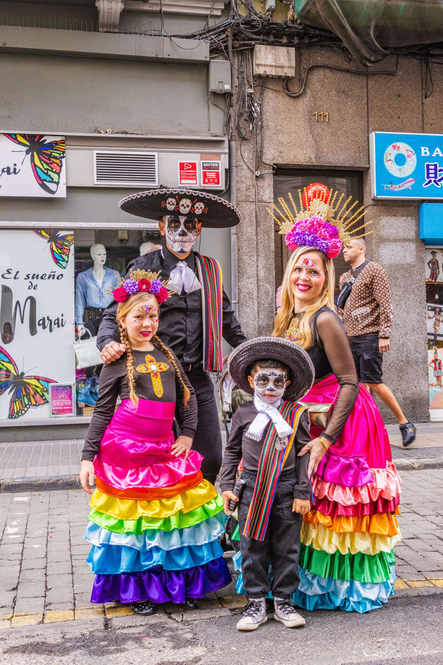 Four sequential photos show performers in vibrant rainbow-colored ruffled dresses dancing on a city street.
