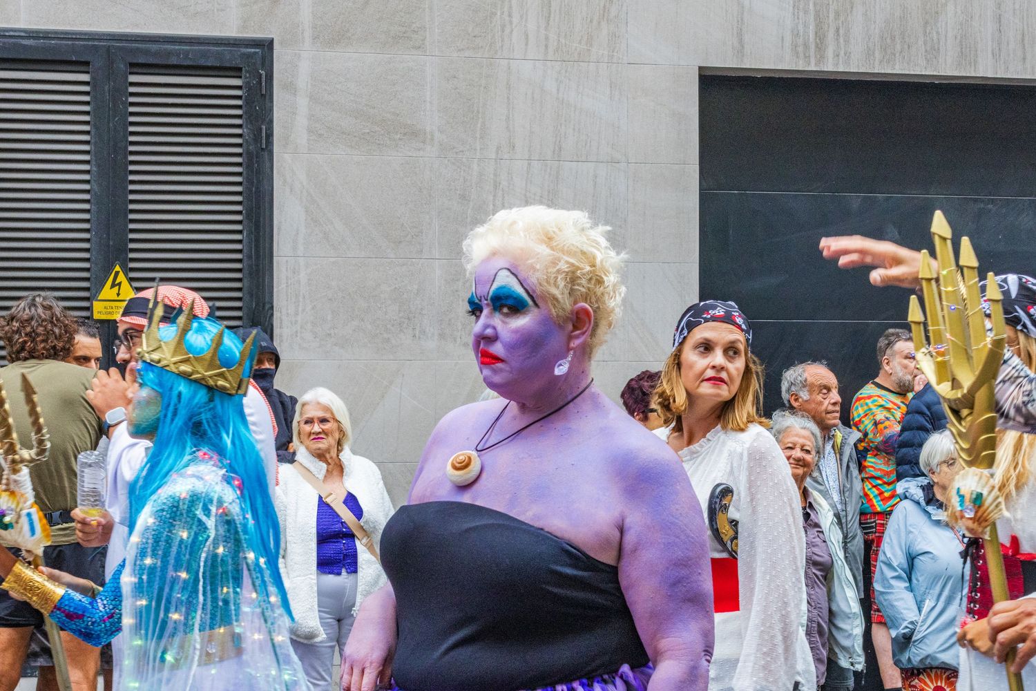 Colorful parade participants in creative costumes and body paint celebrate at a Pride festival event.