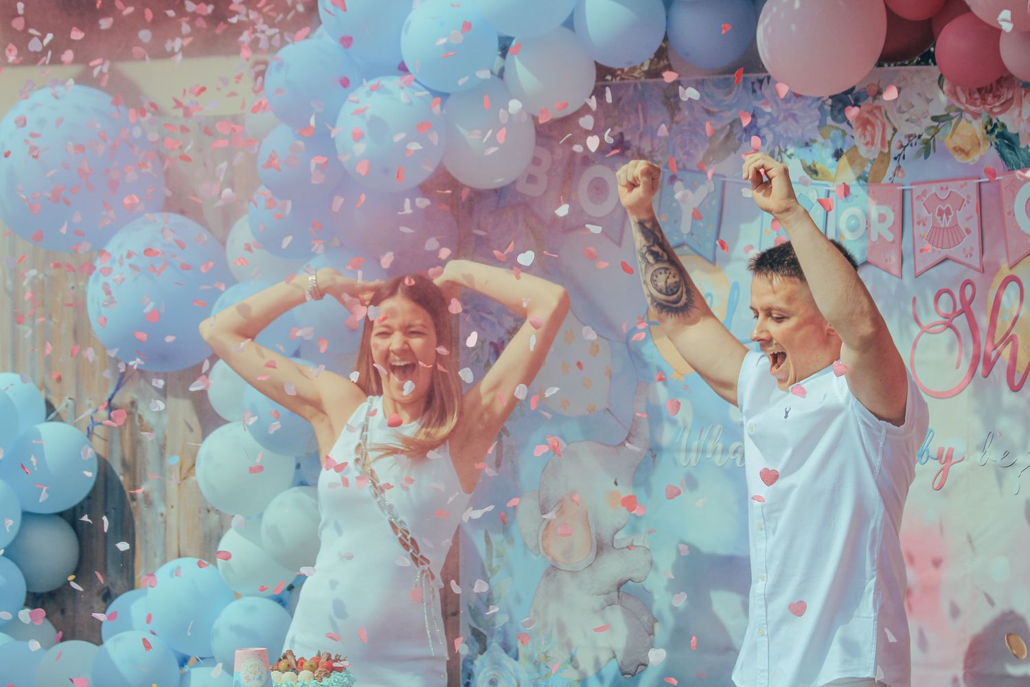 People in white outfits dance and celebrate amidst colorful powder and confetti during a festive event.