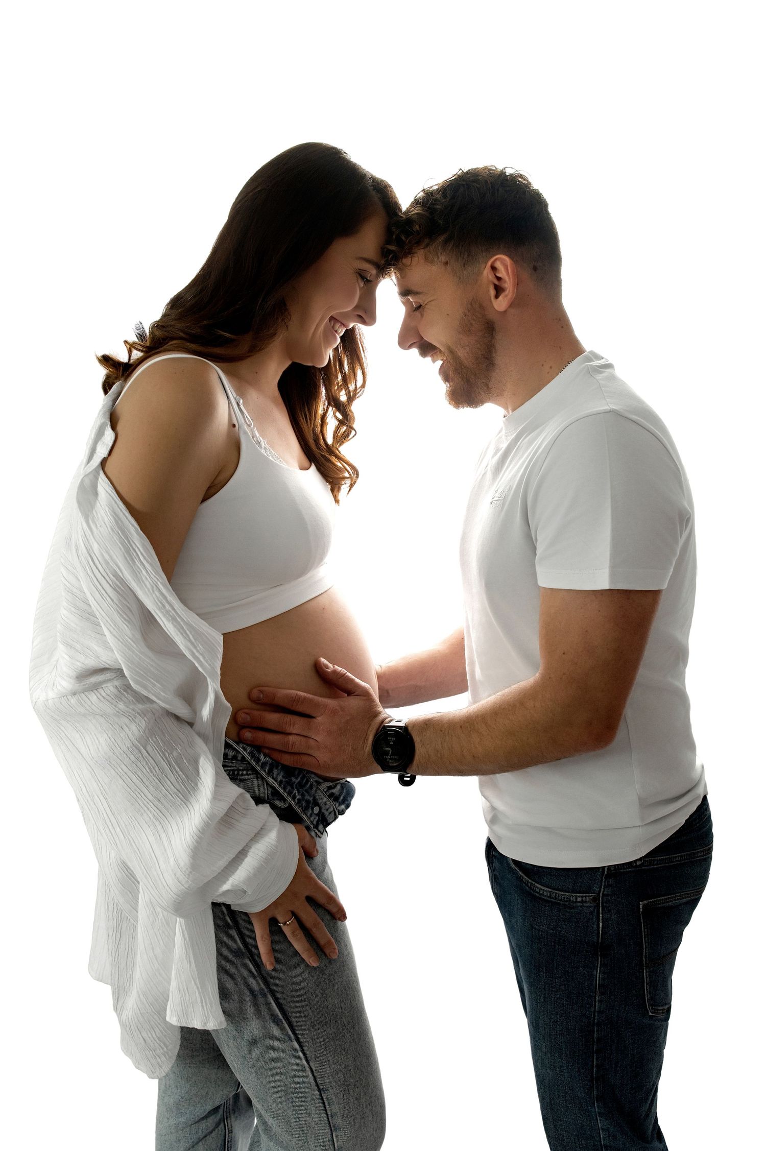 A series of maternity photos showing a couple in white tops embracing and cradling a pregnant belly against a white background.