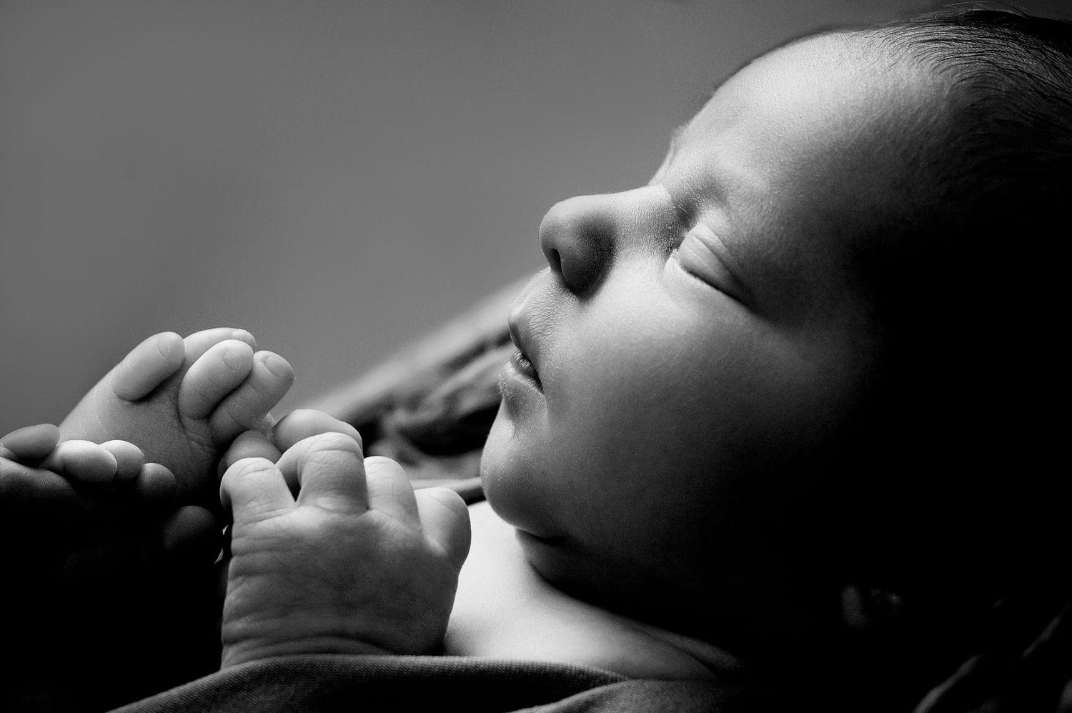 Artistic black and white close-up profile of a sleeping newborn.