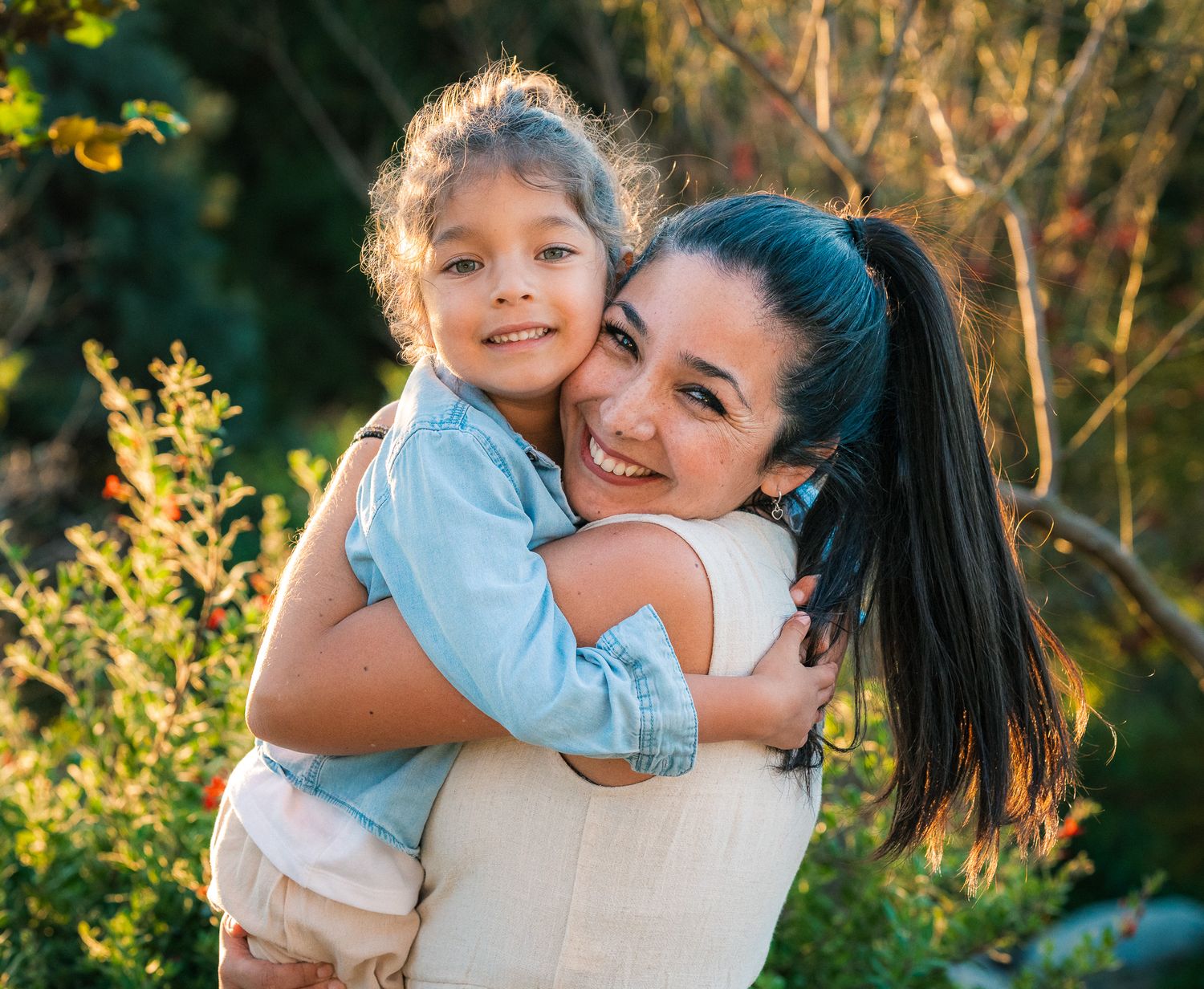 Candid family moment captured in golden sunlight against natural outdoor backdrop.