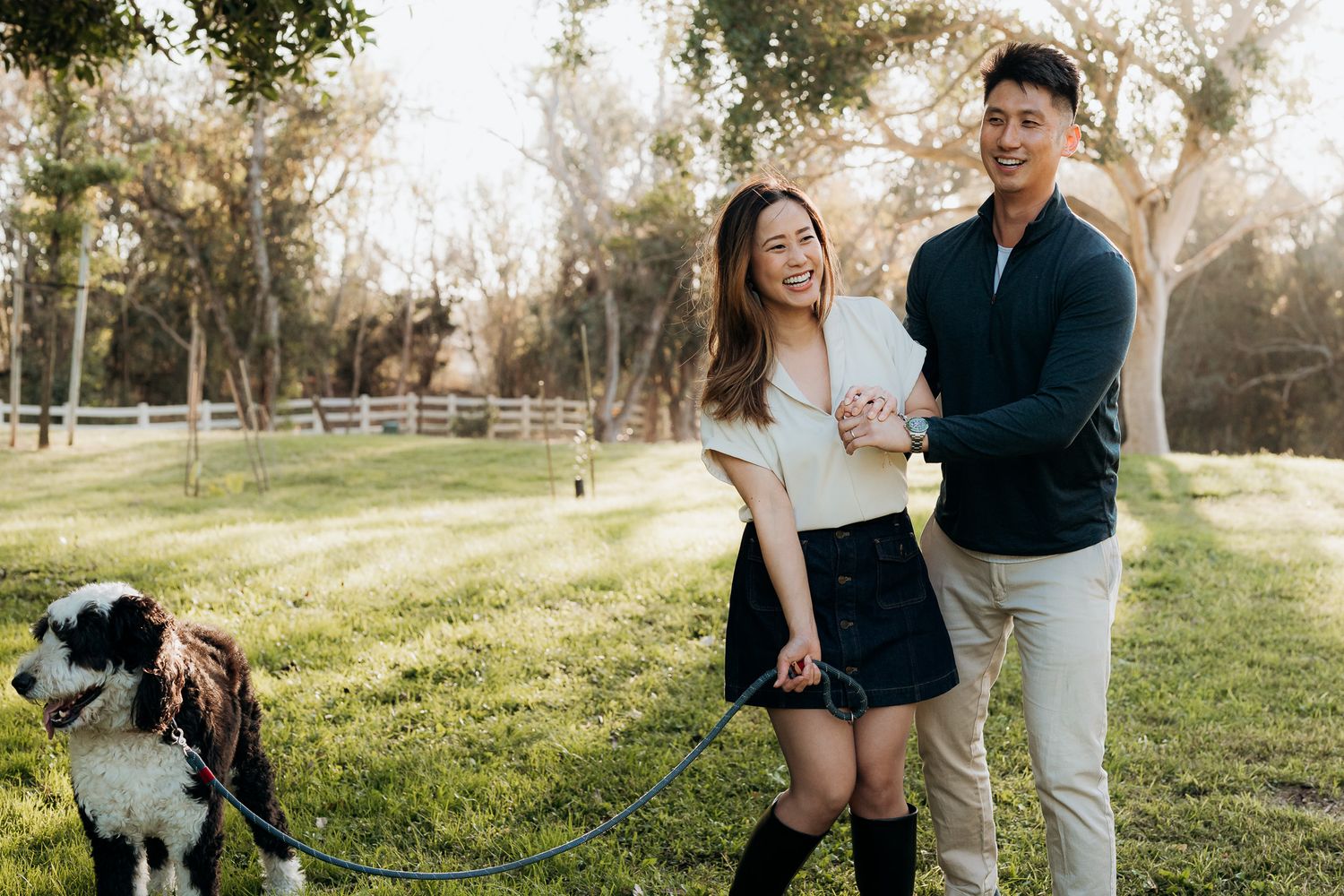 Couple sharing joyful moments while dancing outdoors in a grassy field during golden hour.