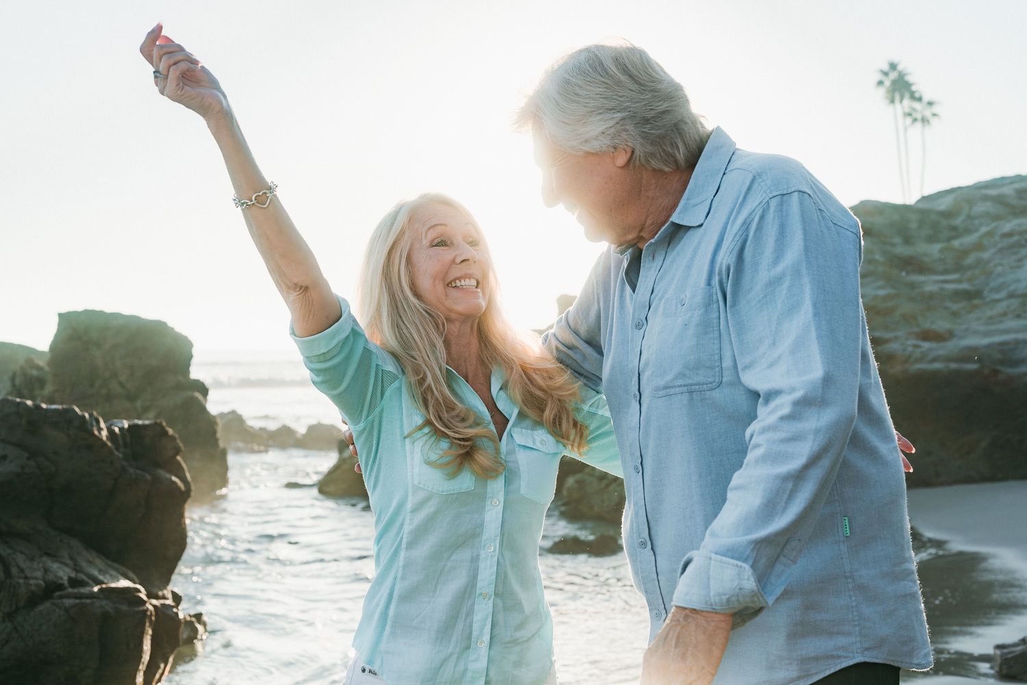 Family shares joyful moments together on coastal rocks during golden hour photoshoot.