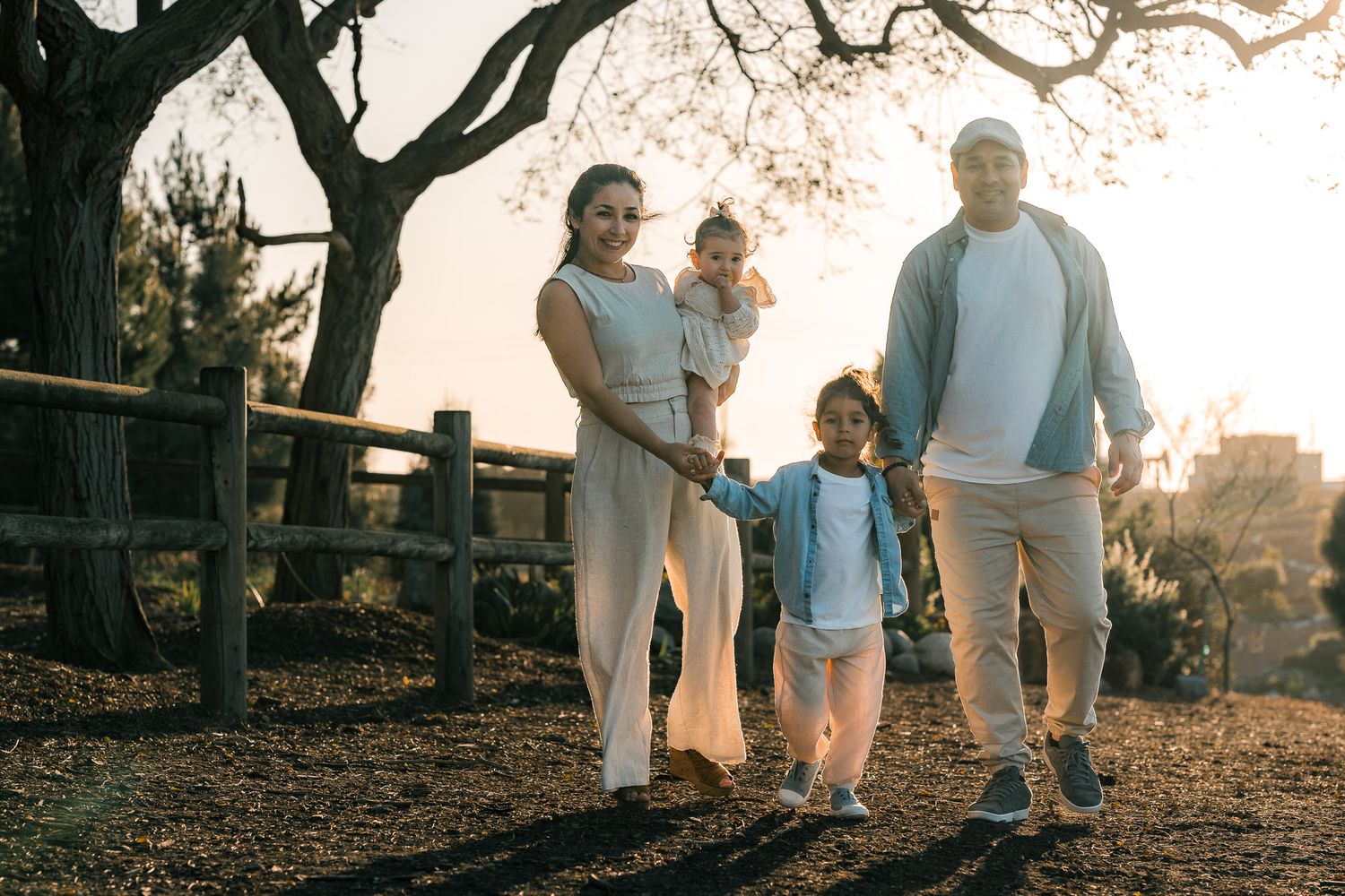Family members walking together along a rustic wooden fence path at sunset.