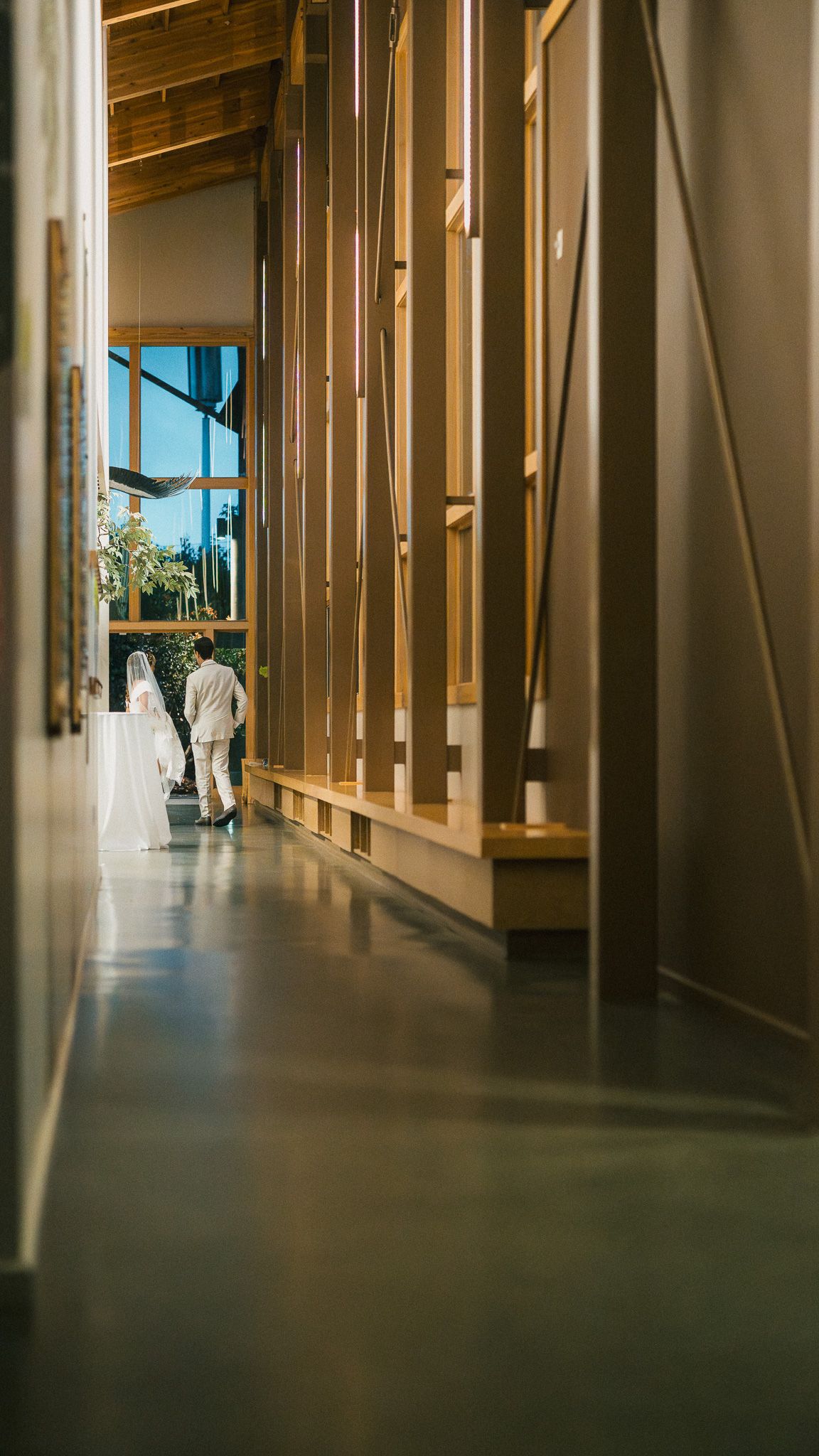Long empty corridor with wooden wall panels and natural light streaming through windows creating dramatic shadows.