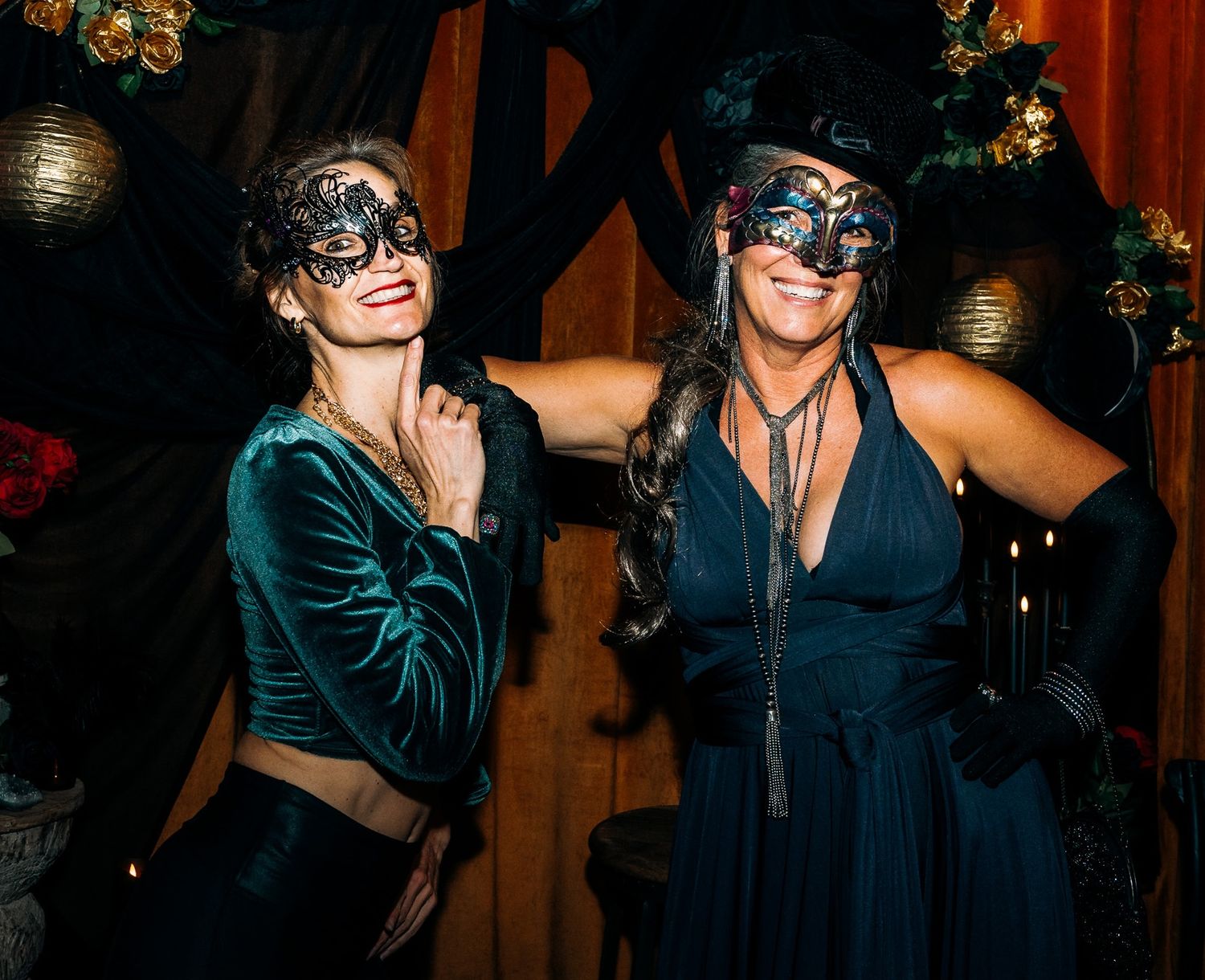 People wearing masquerade masks dance and celebrate at an elegant evening party with warm lighting and festive decor.