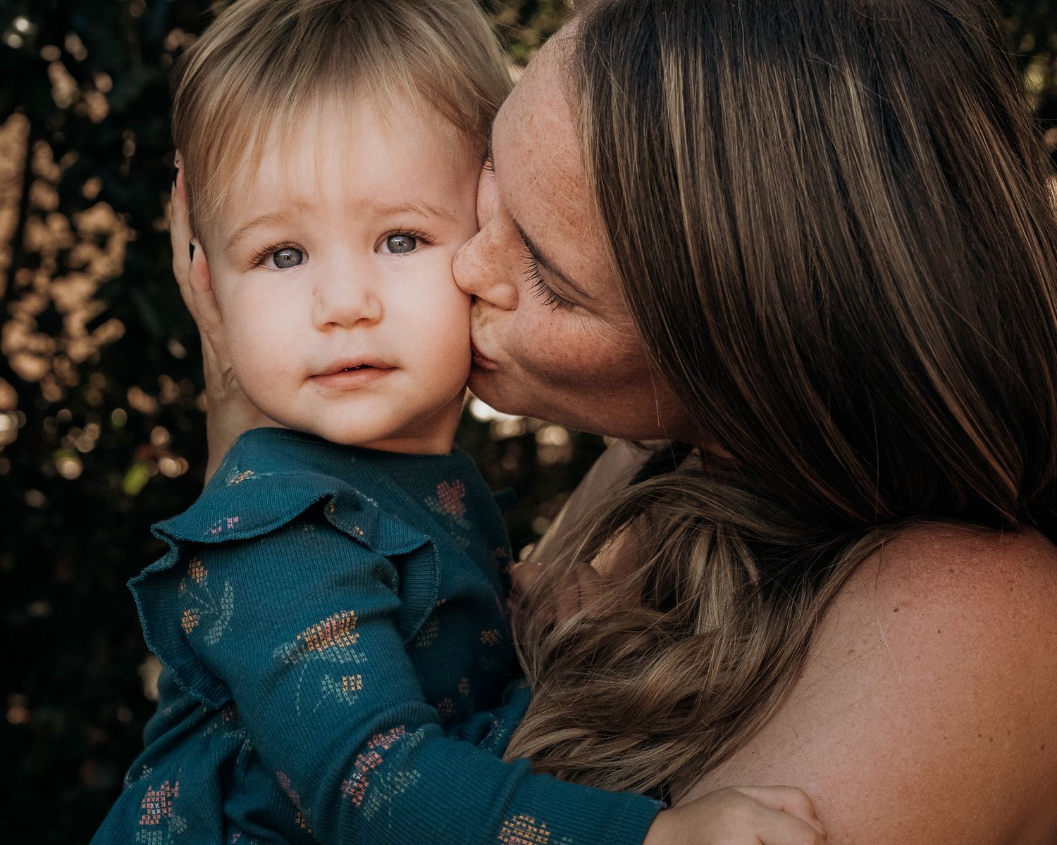 A series of tender moments between parent and child shown in connected photographs with dark natural background.