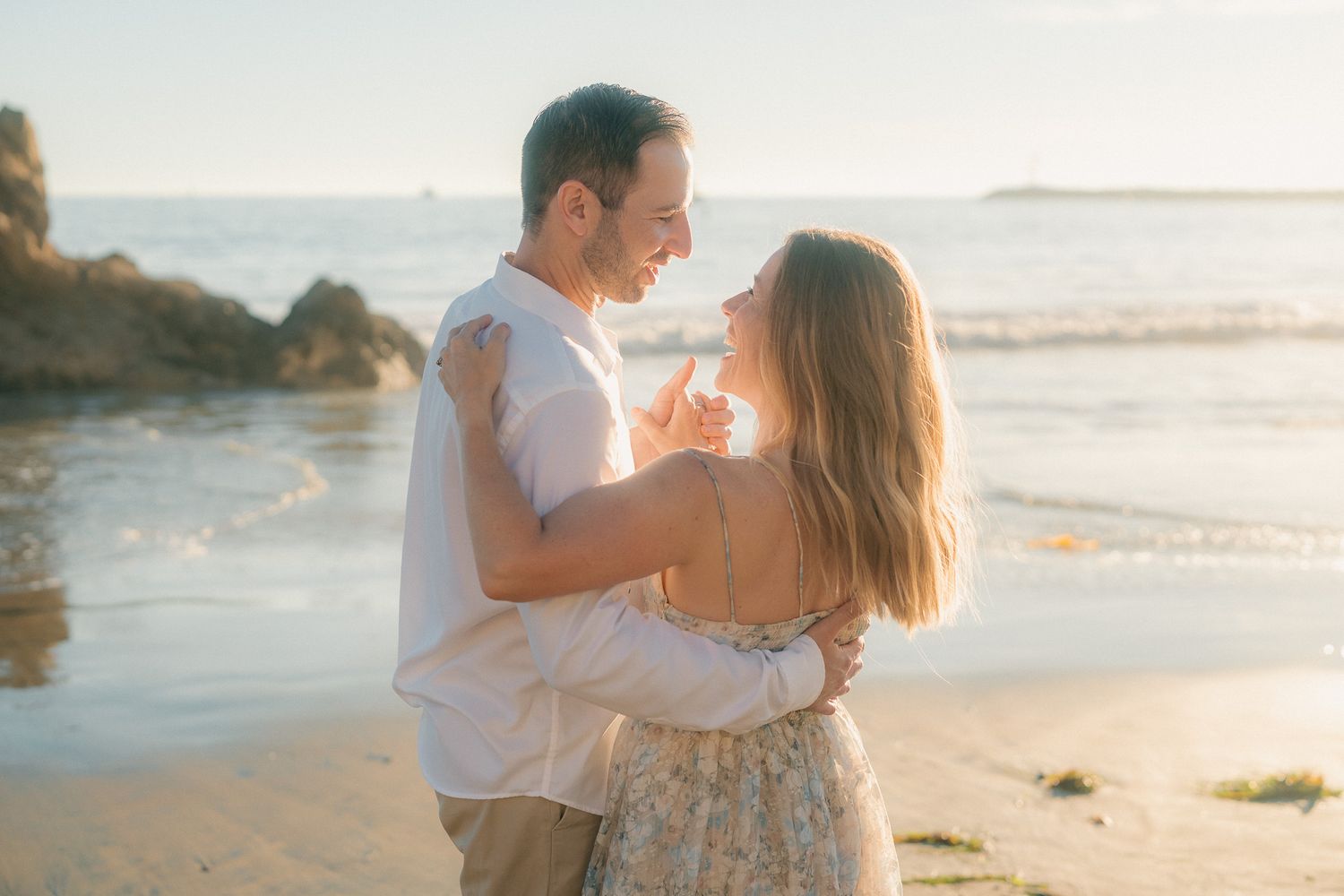 A couple shares romantic moments on a sandy beach at sunset during a photo session.