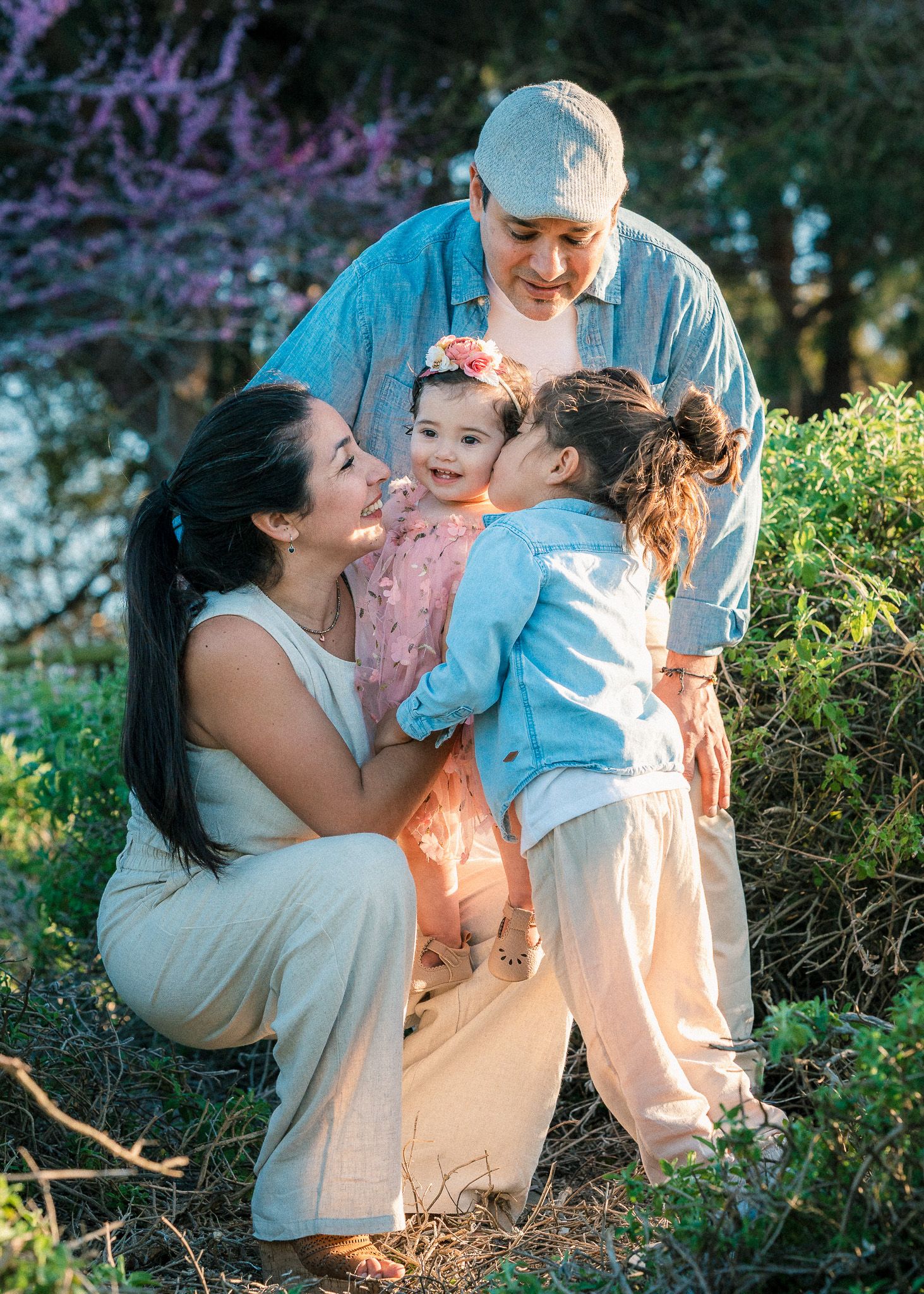 Loving family embraces during sunset photoshoot among blooming garden flowers.
