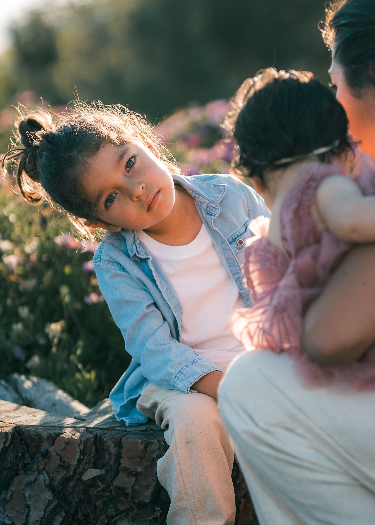 Children sit together on a stone wall at sunset, creating a warm and candid outdoor portrait - Mariano Alvarez, Newport Beach photography