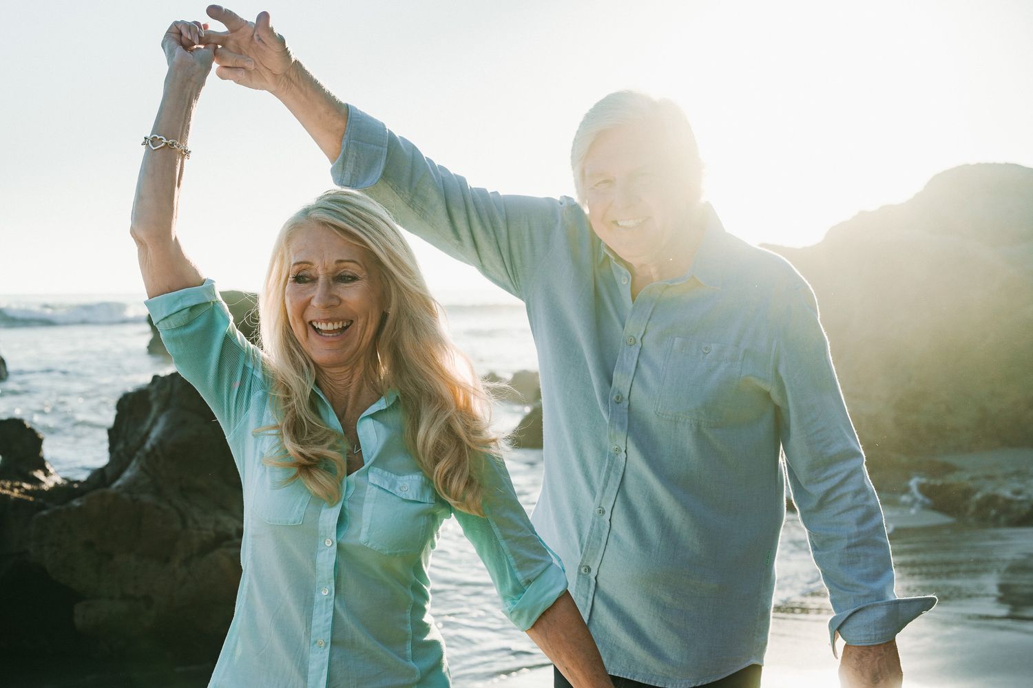 Couple enjoying a romantic sunset moment together on a beach with lens flare and ocean views.