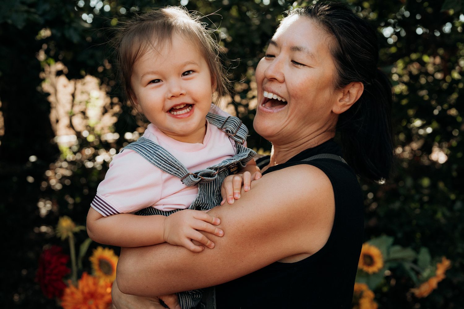 A joyful moment of laughter and embrace captured outdoors during golden hour lighting.