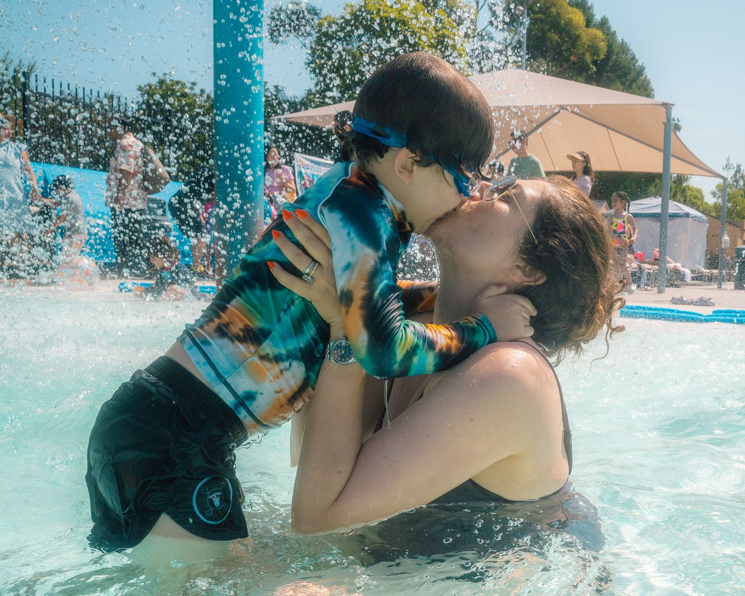 Mother and son kissing while playing in the pool on a hot summer afternoon - Newport Beach Family Photographer