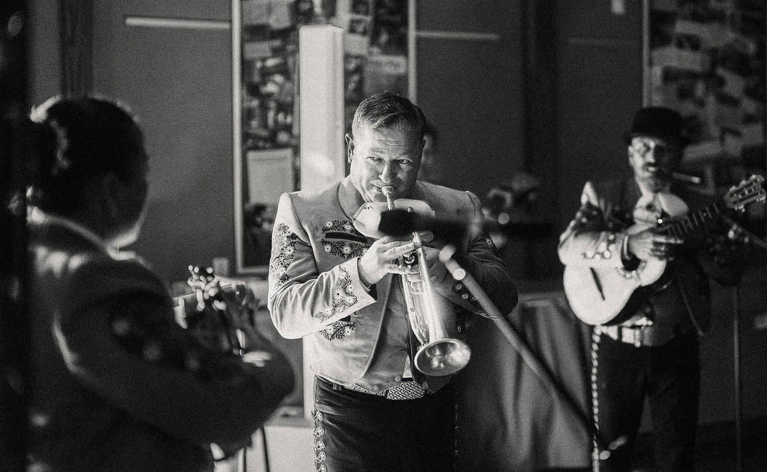 A black and white photo series showing musicians performing with instruments in a dimly lit venue.