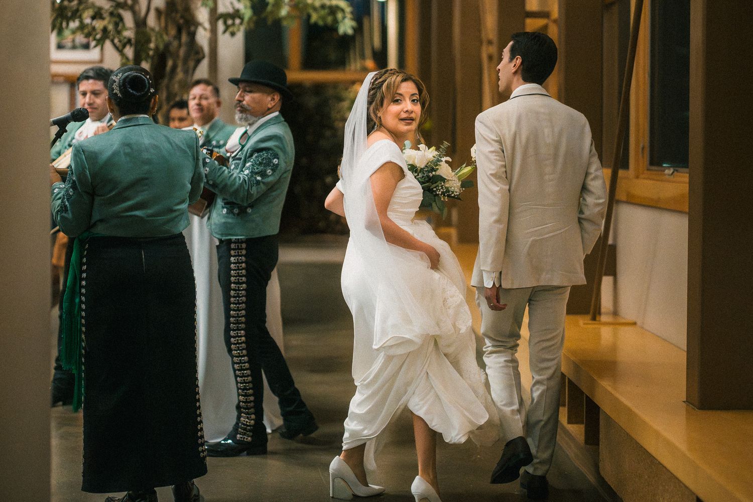 Wedding guests and attendees mingling in a dimly lit indoor reception venue with wooden accents.