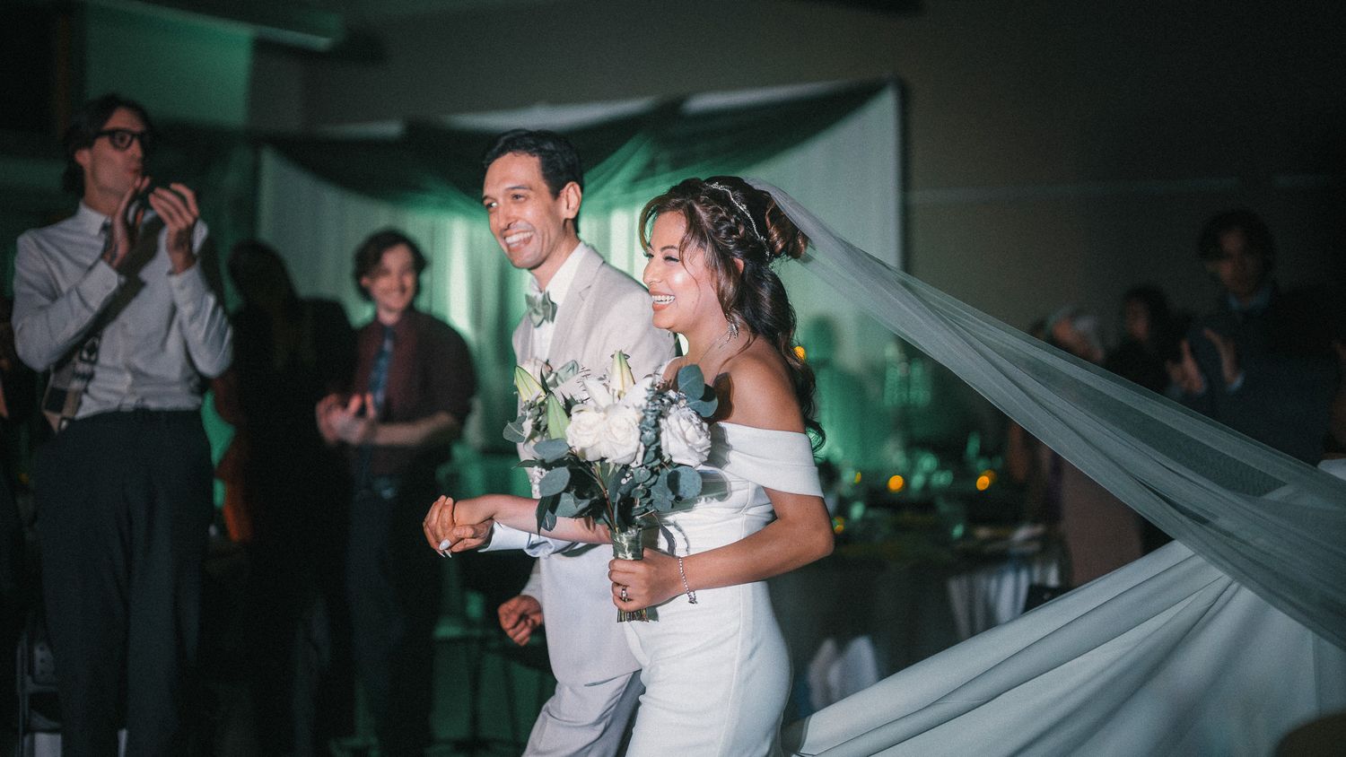 Couples dancing together during a wedding reception with green ambient lighting and elegant decor.