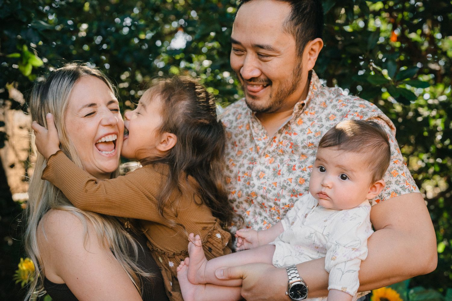 A joyful family shares laughter and embraces while spending time together outdoors in natural sunlight.