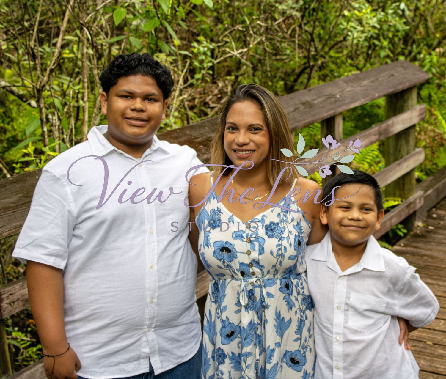 Family smiling together during an outdoor portrait session by View The Lens Studio.