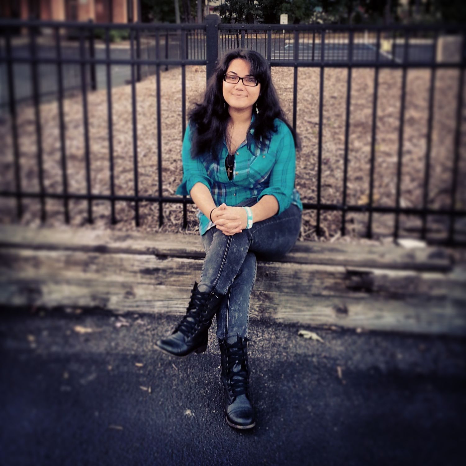 Outdoor portrait of a woman sitting beside a fence during a natural light photography session.