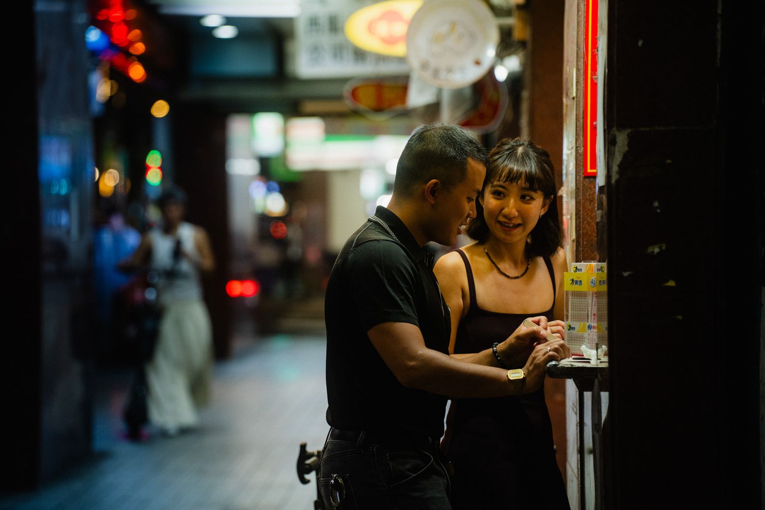 Candid couple scratching Taiwan lottery tickets together at night in Ximending, Taipei
