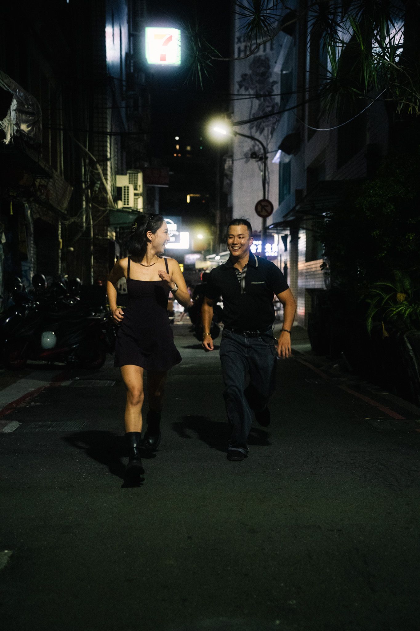 Candid couple running together through the streets of Ximending during a Taipei night photoshoot