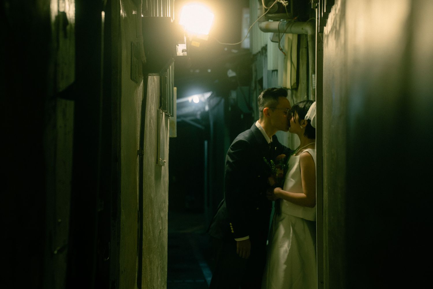 Bride and groom kissing in a narrow alley near Huaxi Street Night Market during a cinematic Taipei photoshoot