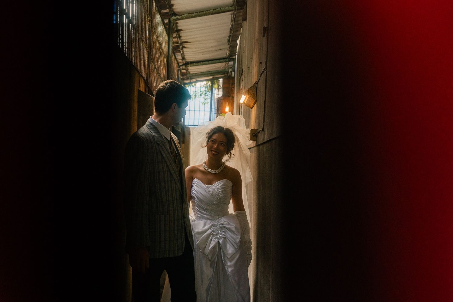 Emily and Nik sharing a quiet moment in a dark Taipei alley with warm light and a red foreground