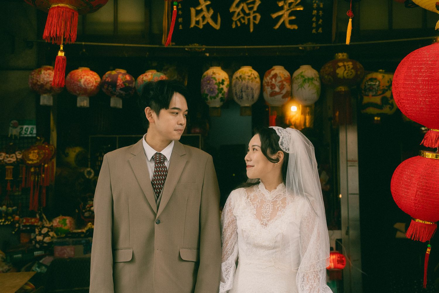Taipei pre-wedding portrait of a bride and groom looking at each other beneath traditional lanterns on Dihua Street
