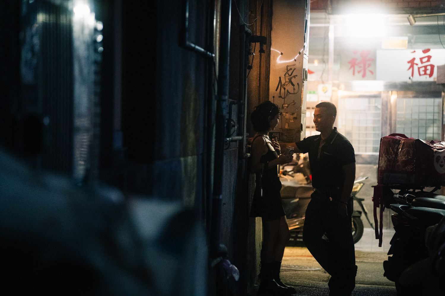 Couple laughing and chatting on the side street during a nighttime Taipei photoshoot