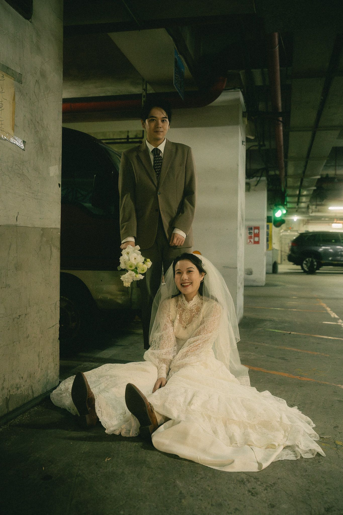 Playful portrait of a bride seated beneath the groom beside a vintage van during a Taipei pre-wedding shoot