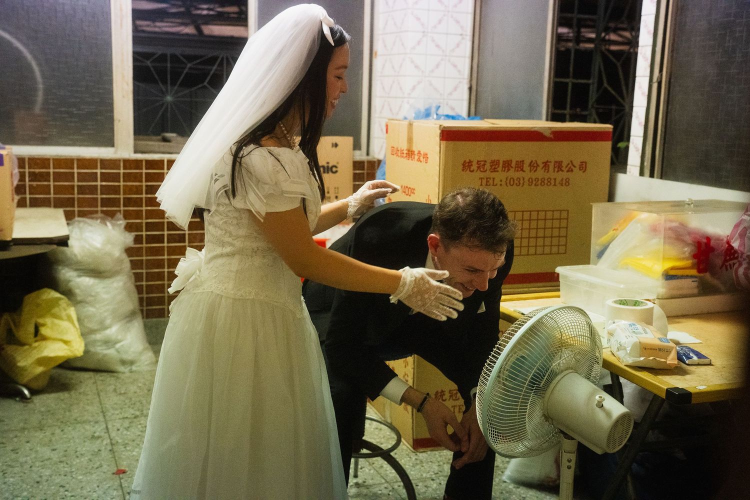 Candid pre-wedding moment of a bride helping her groom wipe his face inside a local Taipei shop